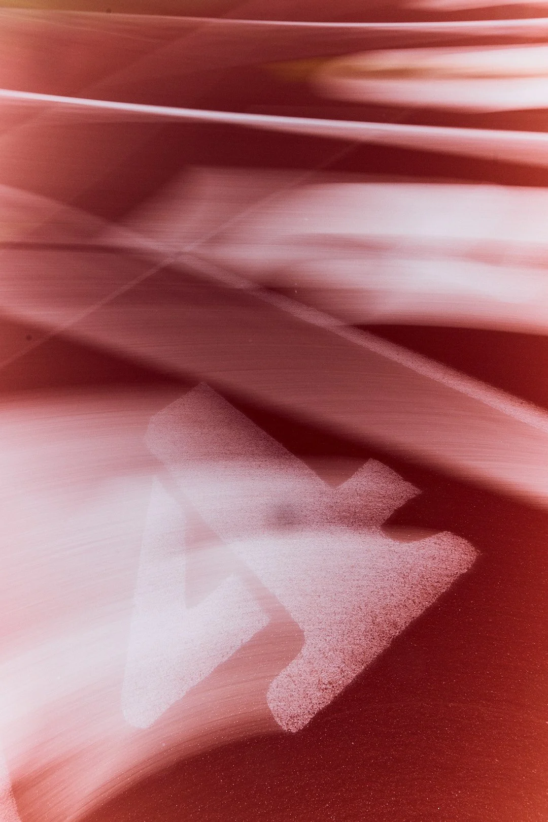 Abstract image with blurred red and white shapes and a silhouette of a chameleon.