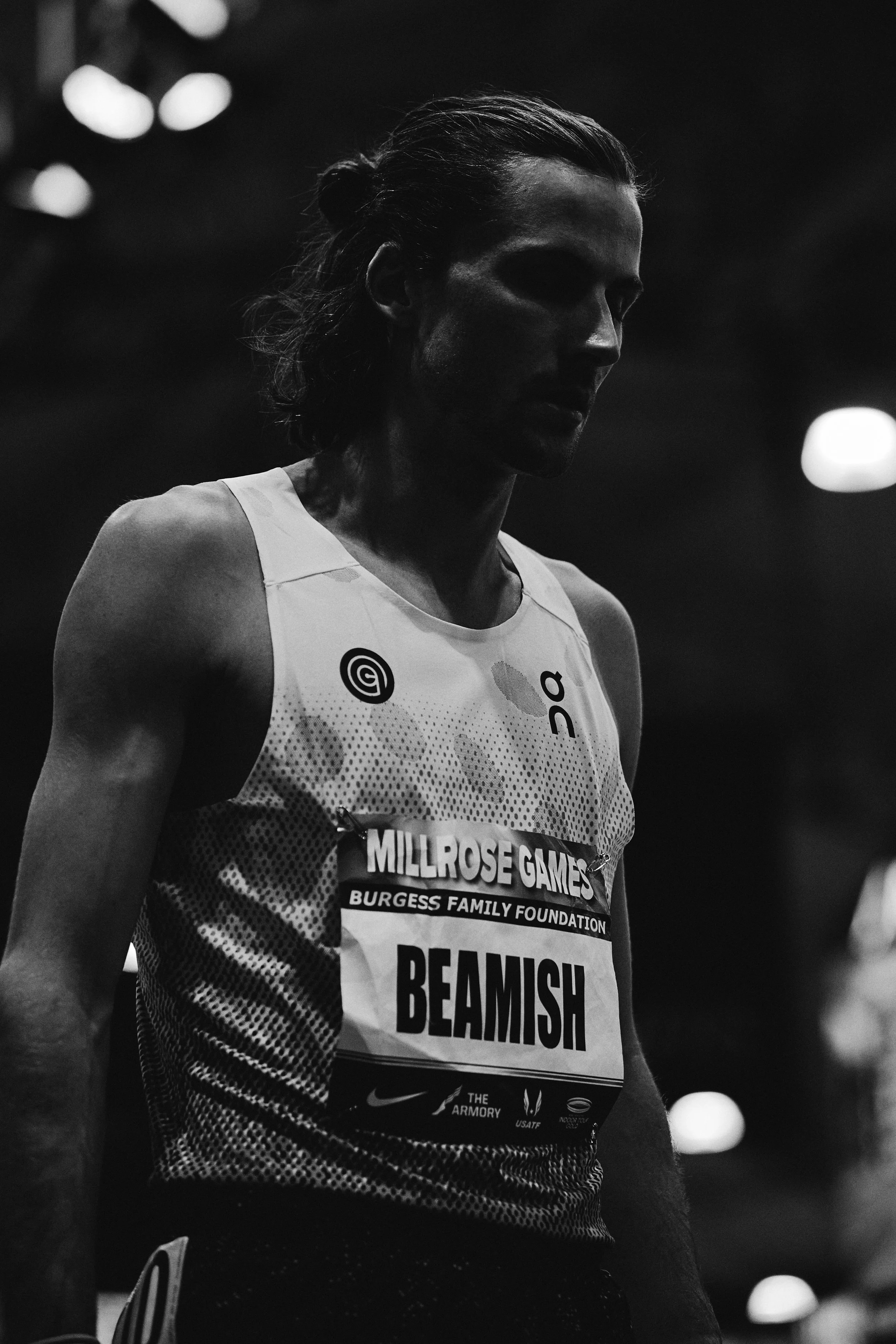 Black and white photo of a male athlete wearing a sleeveless athletic shirt with a race bib labeled 'BEAMISH' and 'Millrose Games'.