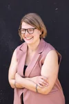 A smiling woman with short blonde hair and glasses