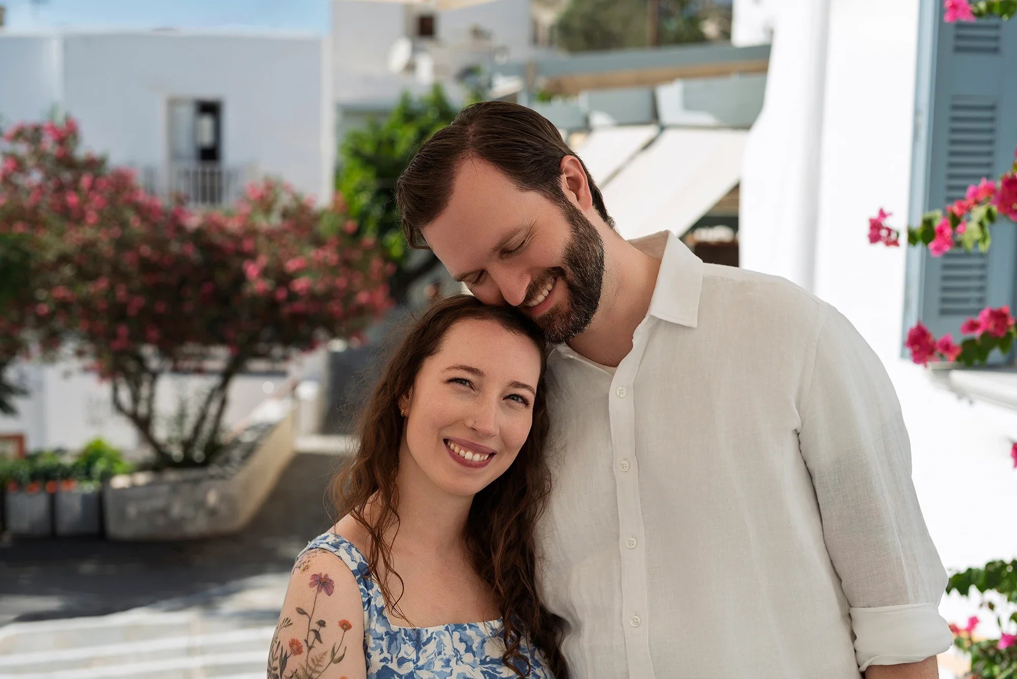 Couple smiling together in a Naxos village with pink bougainvillea in the background