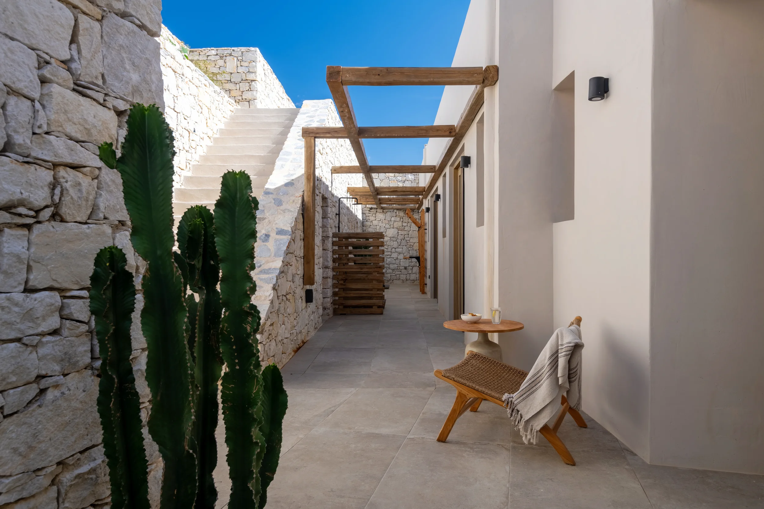 Cycladic villa outdoor corridor with stone wall, wooden pergola and cactus — real estate photographer Naxos Greece