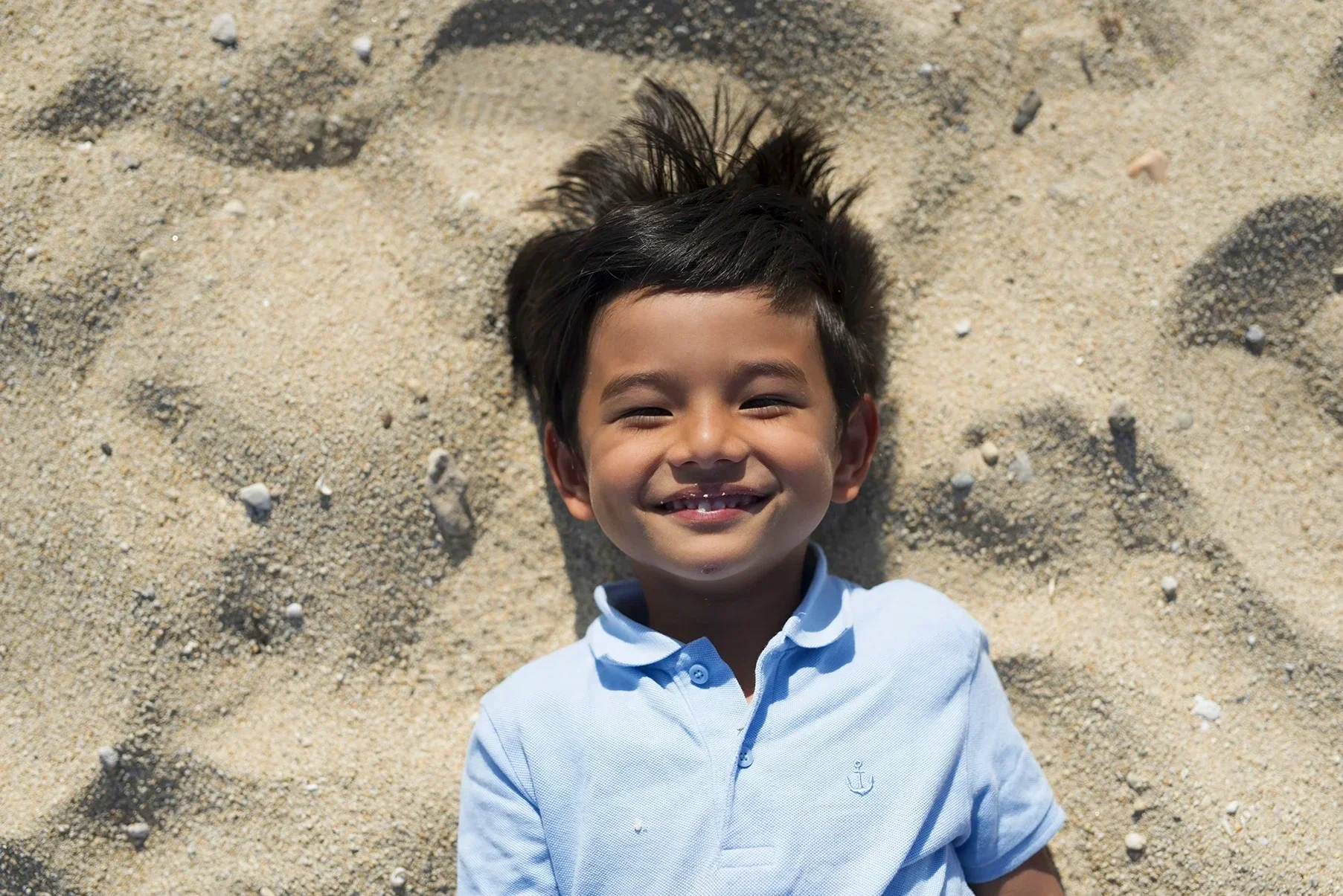 Layflat portrait of a young boy on the sand