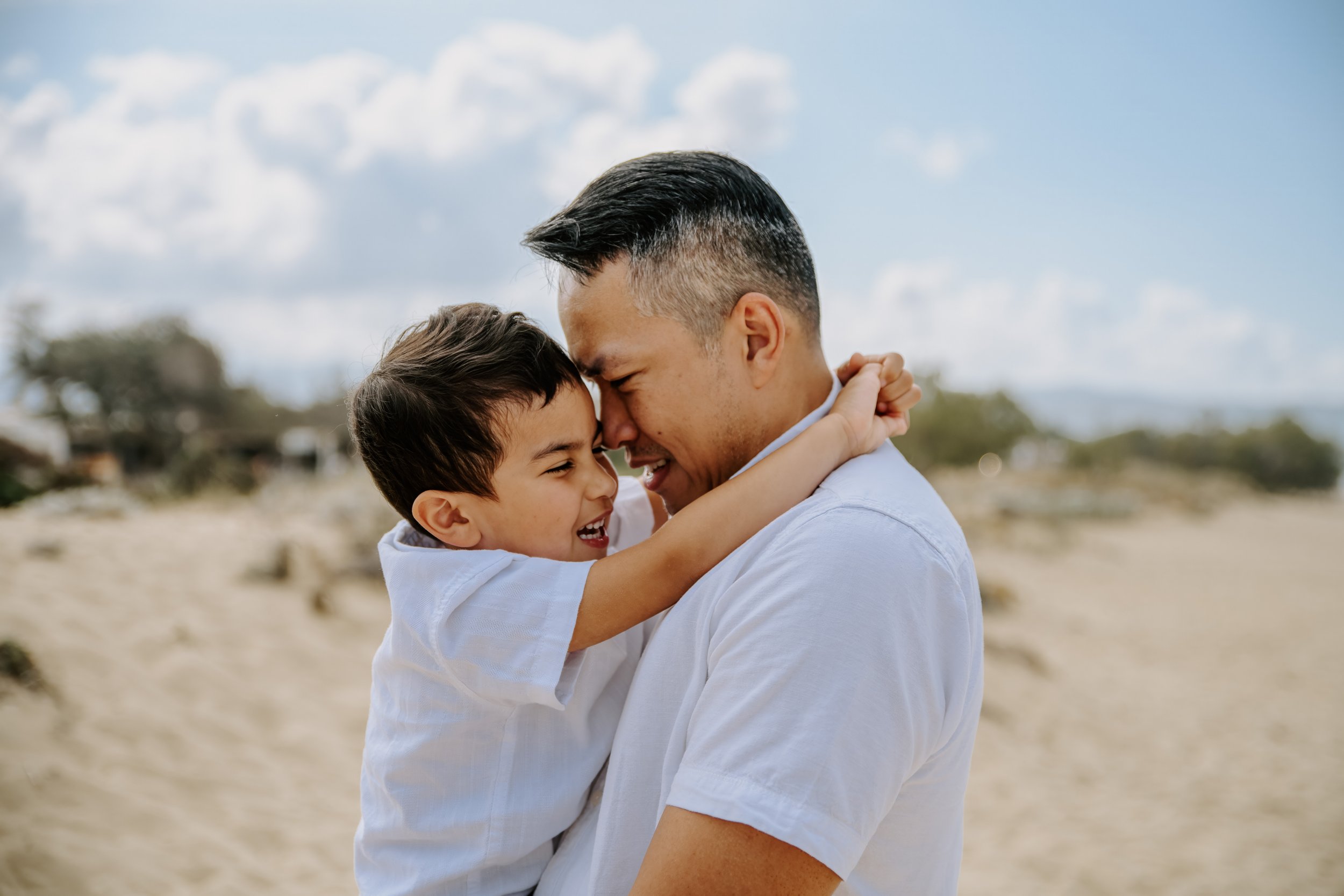 Father and son sharing a joyful moment during a family photoshoot on a Naxos beach.