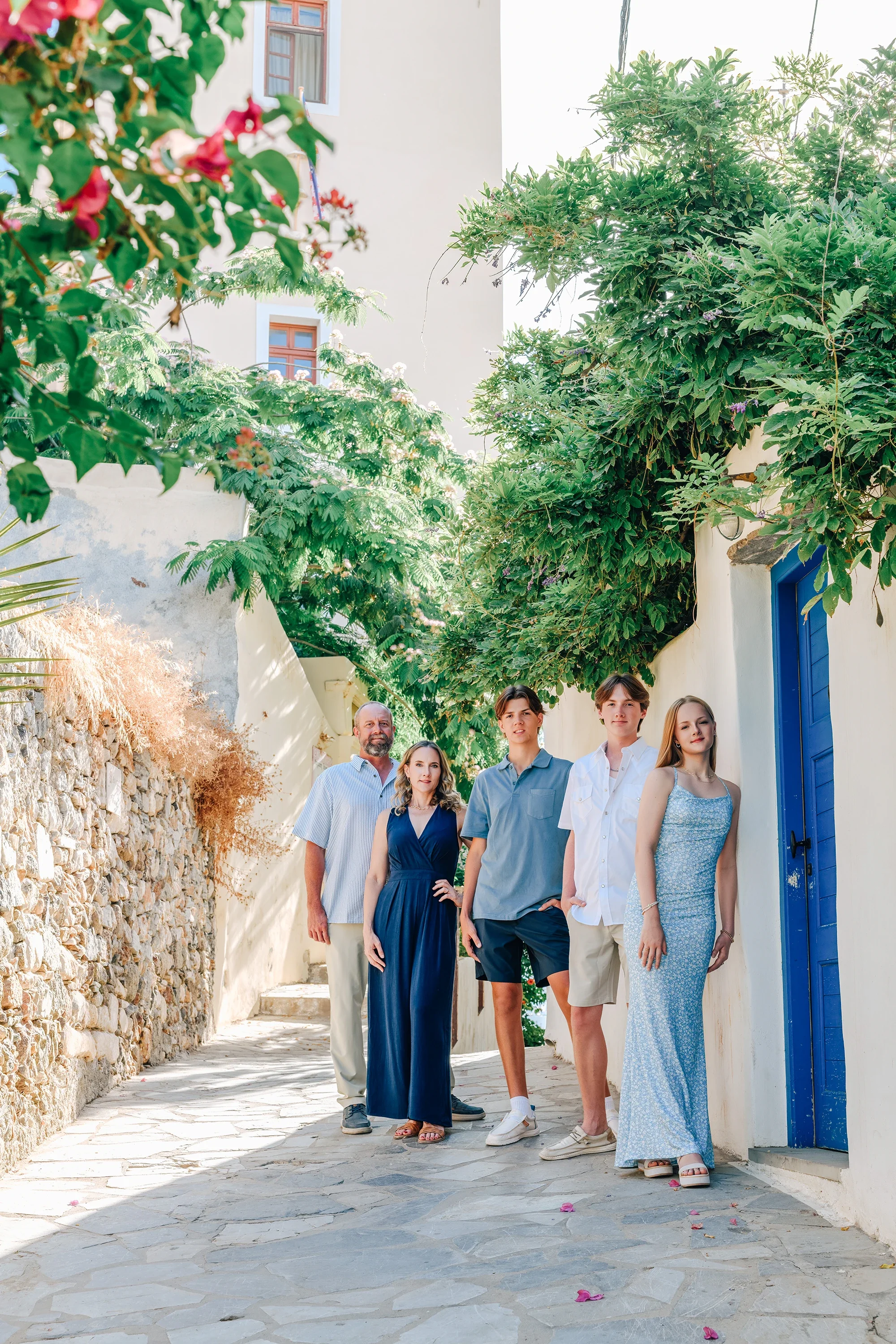 Family of five in a Naxos village alley with bougainvillea and blue door