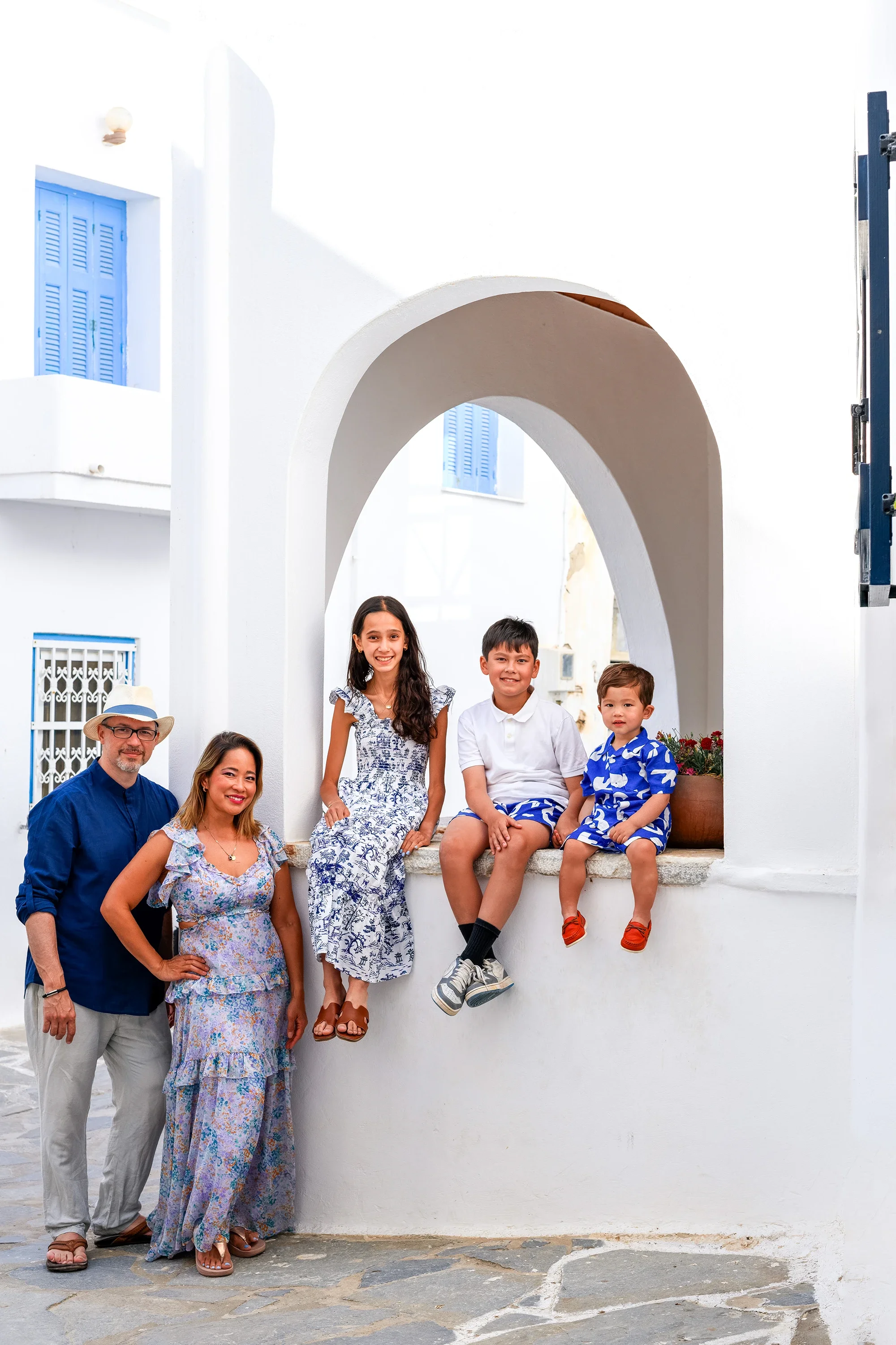 Family of five photographed by a white archway with blue shutters in Naxos