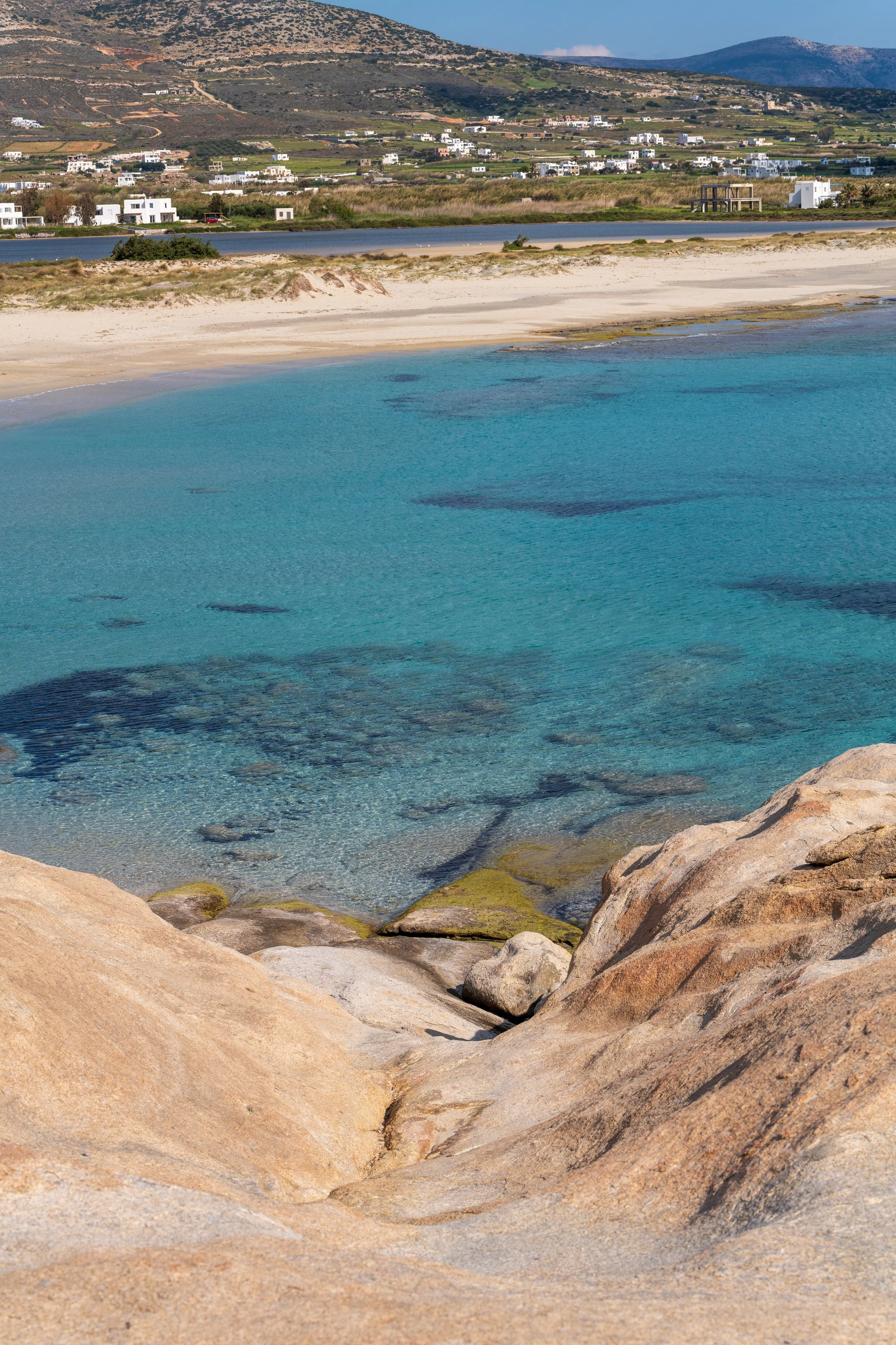 Landscape photography of Mikri Vigla Beach in Naxos Greece with turquoise sea water, rocky foreground and sandy shoreline