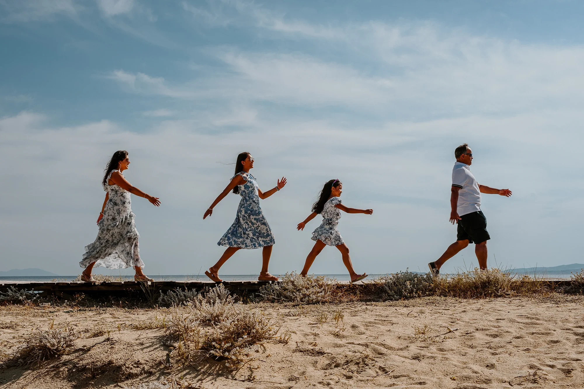 Family walking in a row along a Naxos beach with sea in the background