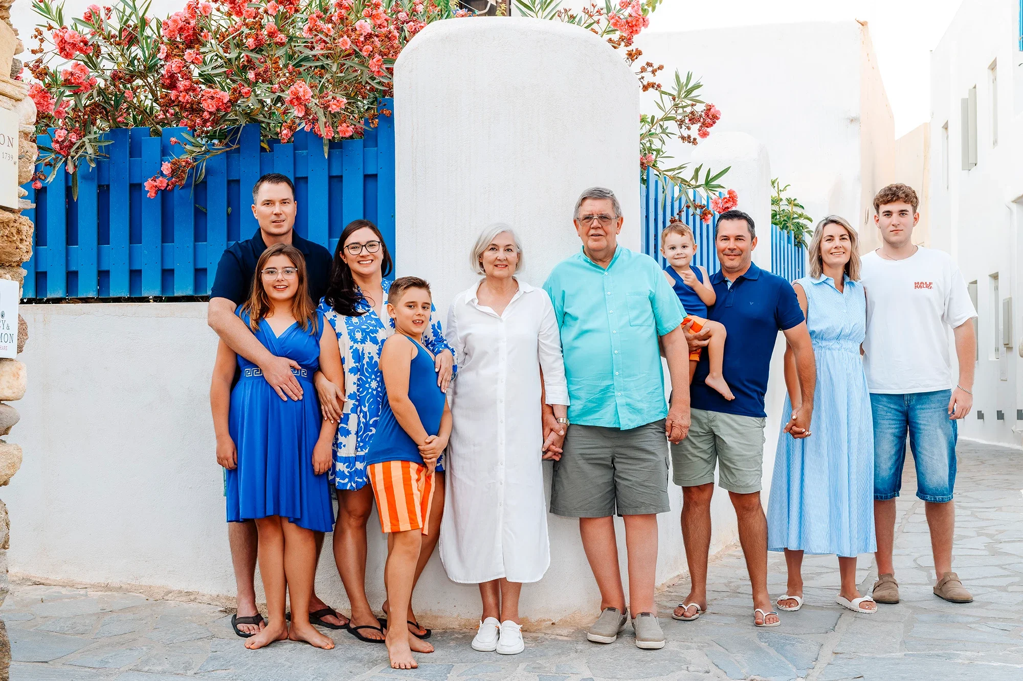 Extended multi generational family photographed in a Naxos village with blue gate and flowers