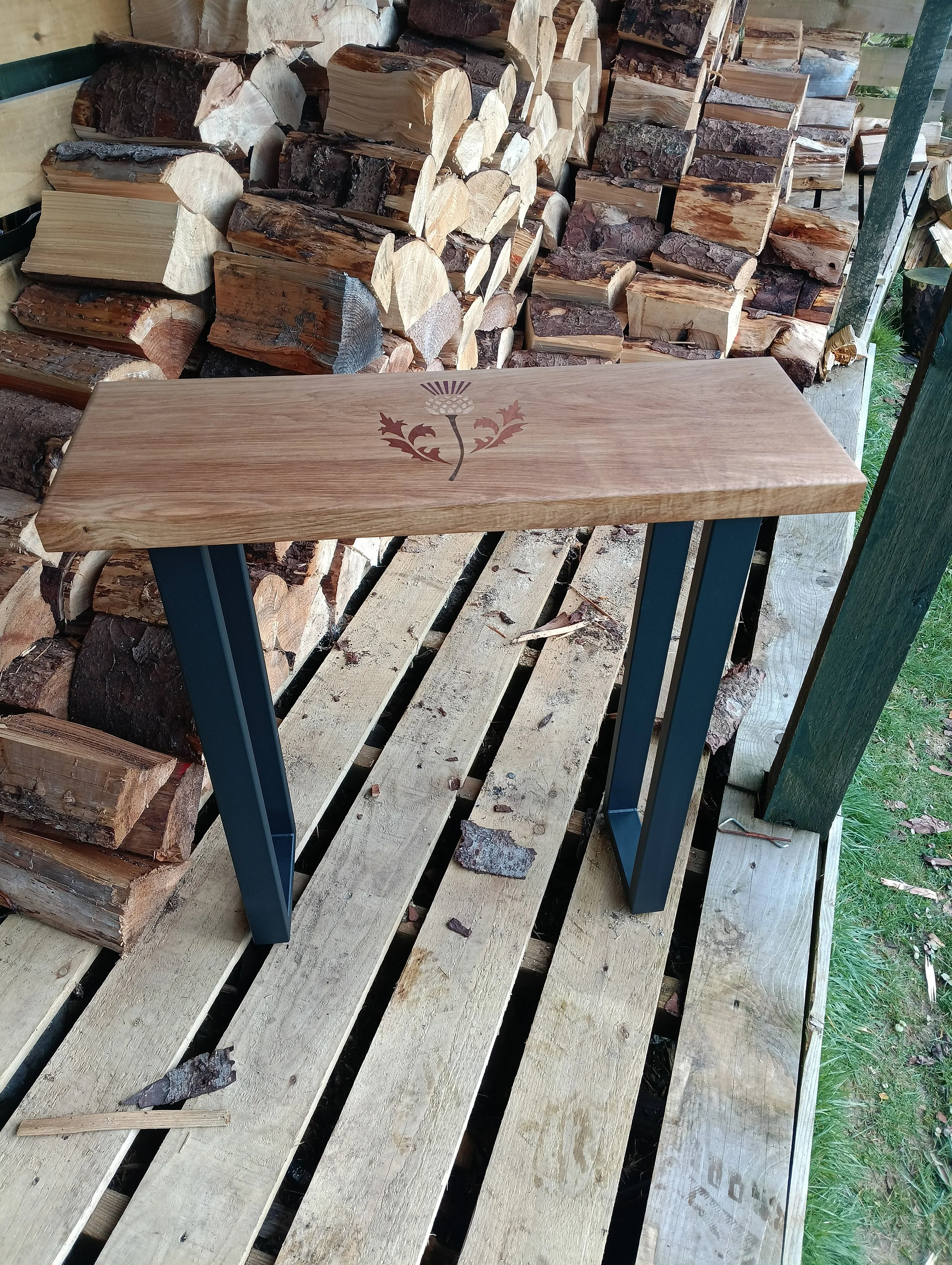 A solid 40mm thick piece of Oak with a Scottish thistle done in Marquetry  with dark metal legs,