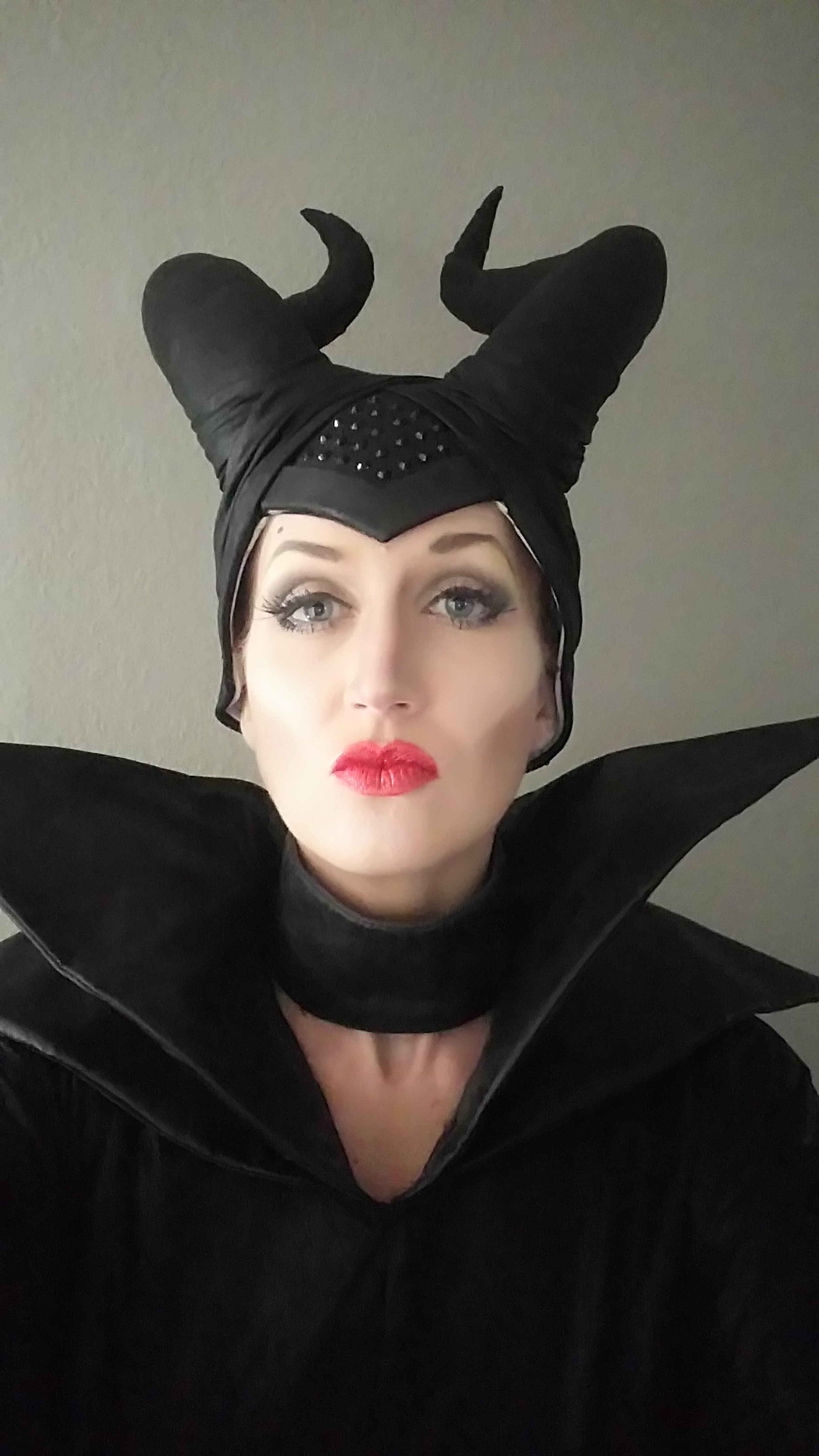 Person dressed as Maleficent from Disney, wearing a black headdress with horns and a black cape with high shoulder accents.