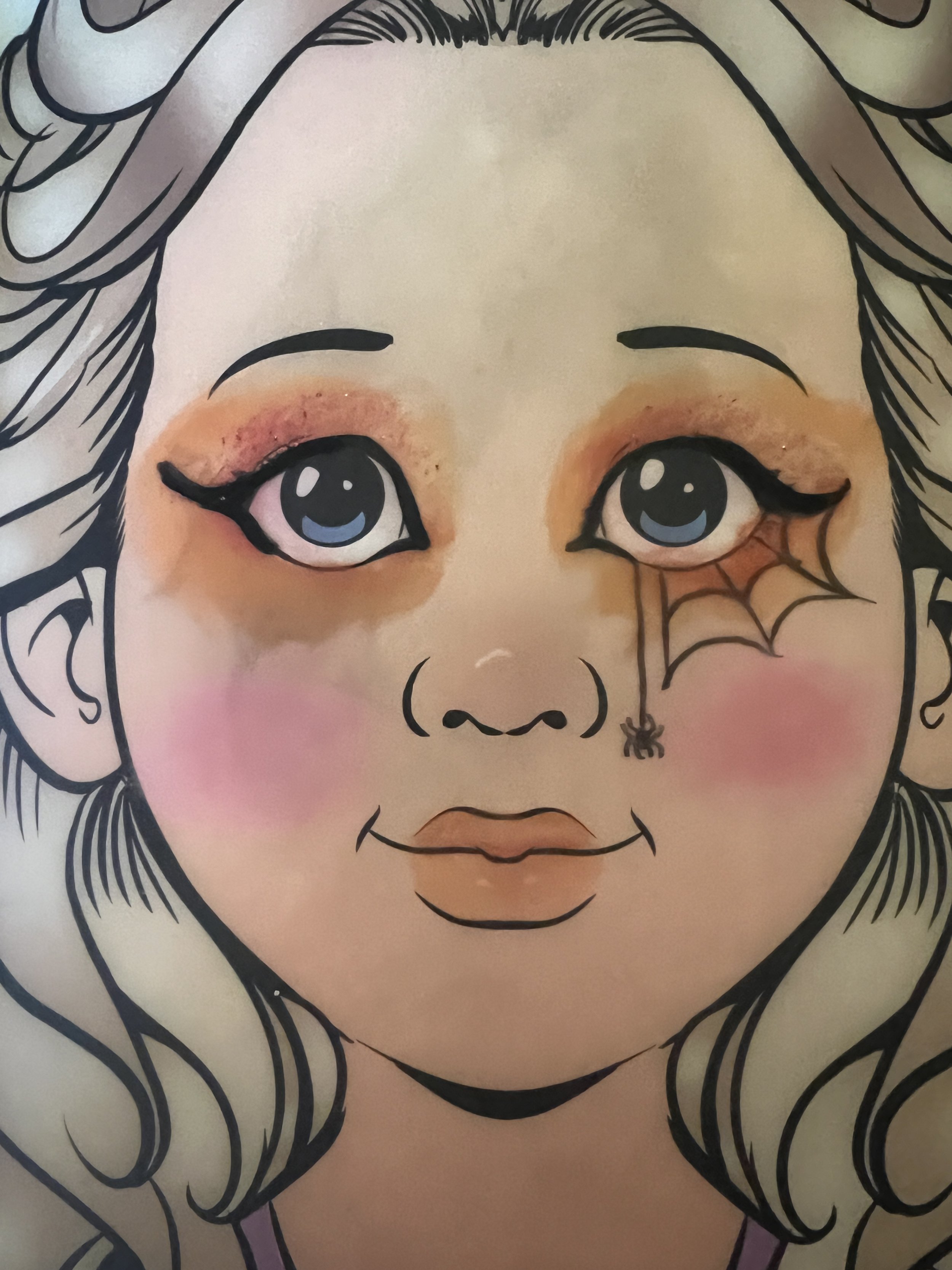 Illustration of a young girl with wavy hair, big blue eyes, and makeup. She has blush on her cheeks, a small spider tattoo near her eye, and a painted spider web under her eye.