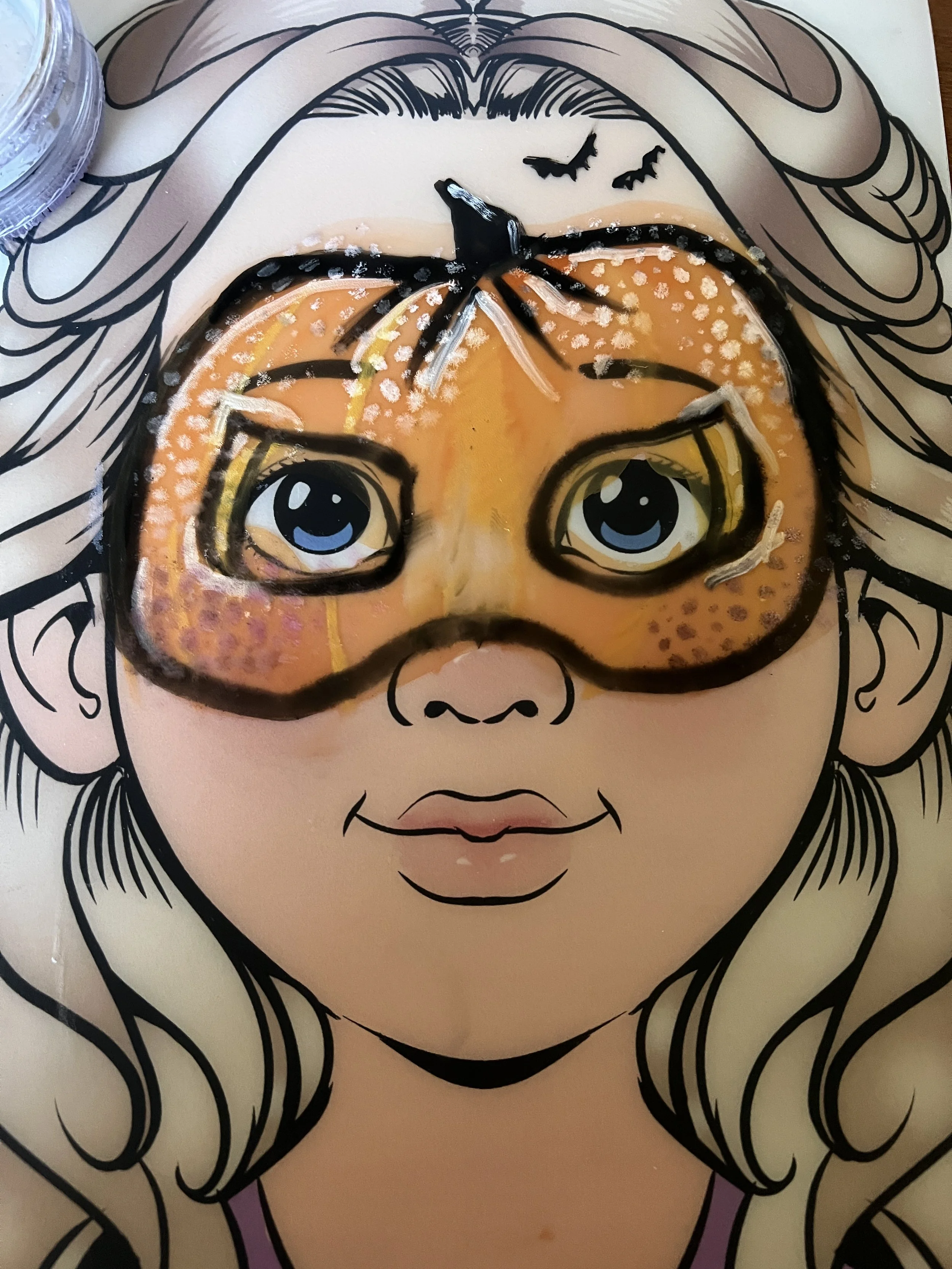 A coloring page illustration of a girl with long hair, and a pumpkin-shaped mask with eyes over her face, part of a Halloween or fall theme.