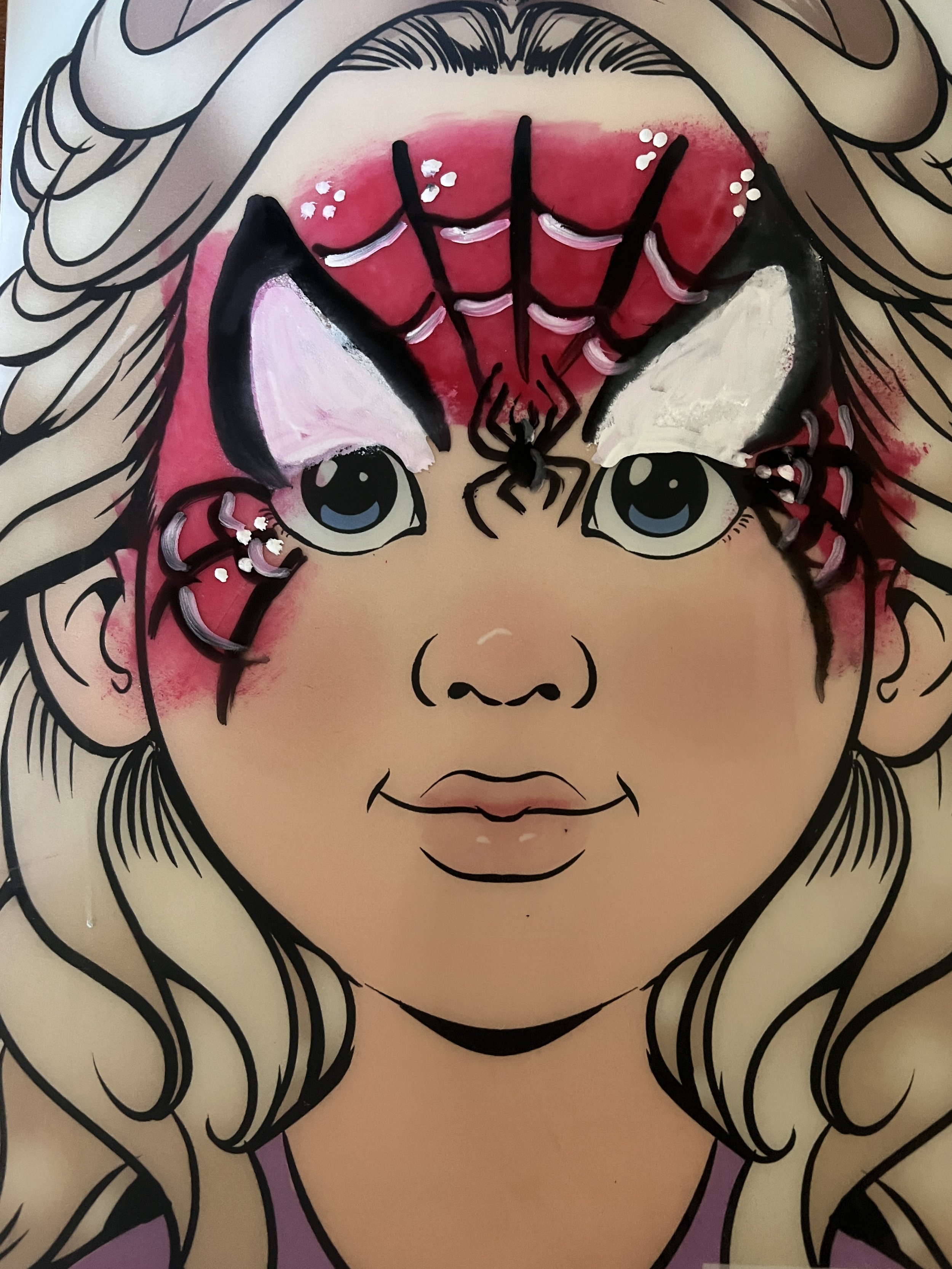 Cartoon girl with blonde hair, pink face paint resembling a spider and web, and decorative white and pink accents around her eyes.