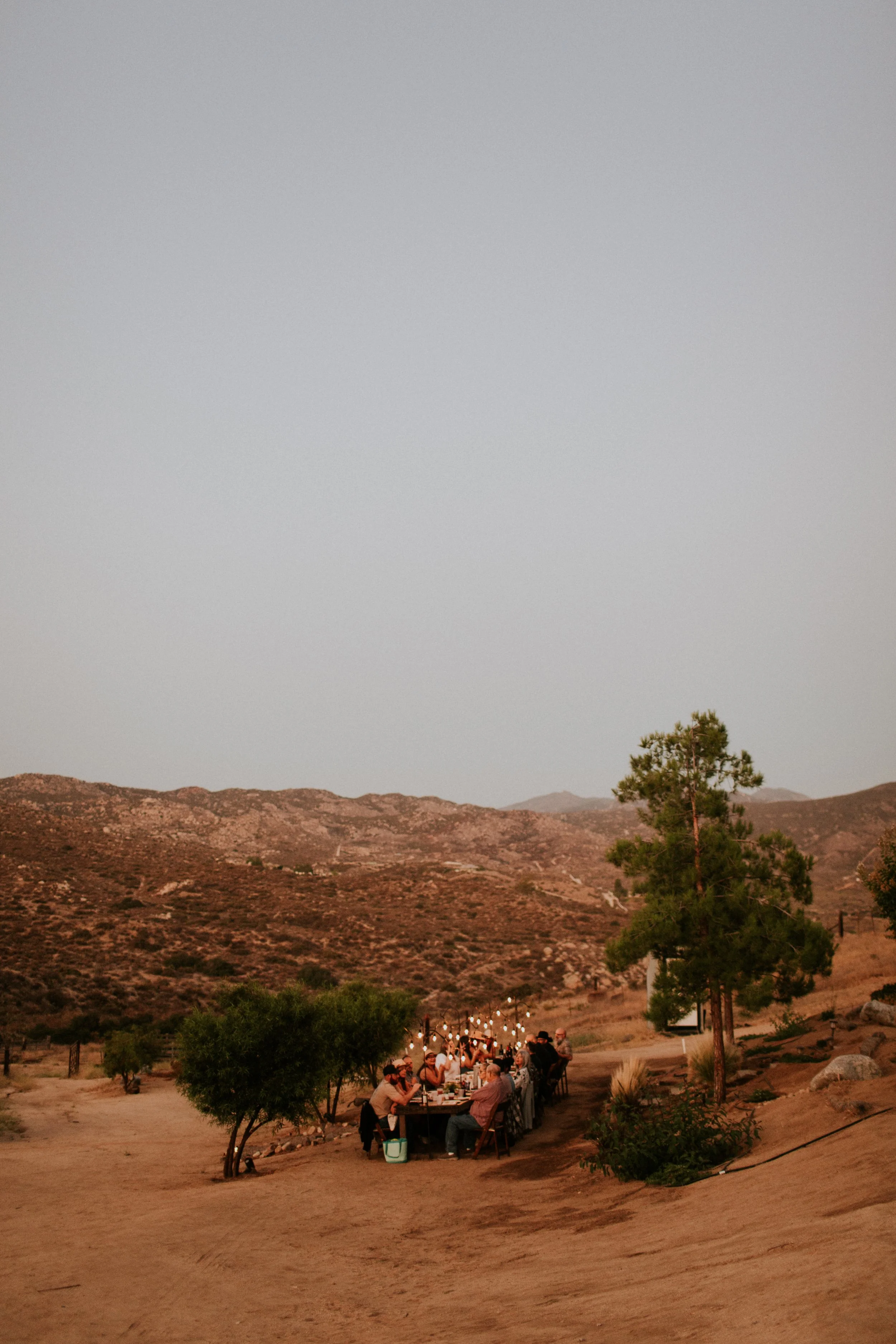 A group of people sitting at a long outdoor table with string lights in Aguanga, new Temecula Wine Country