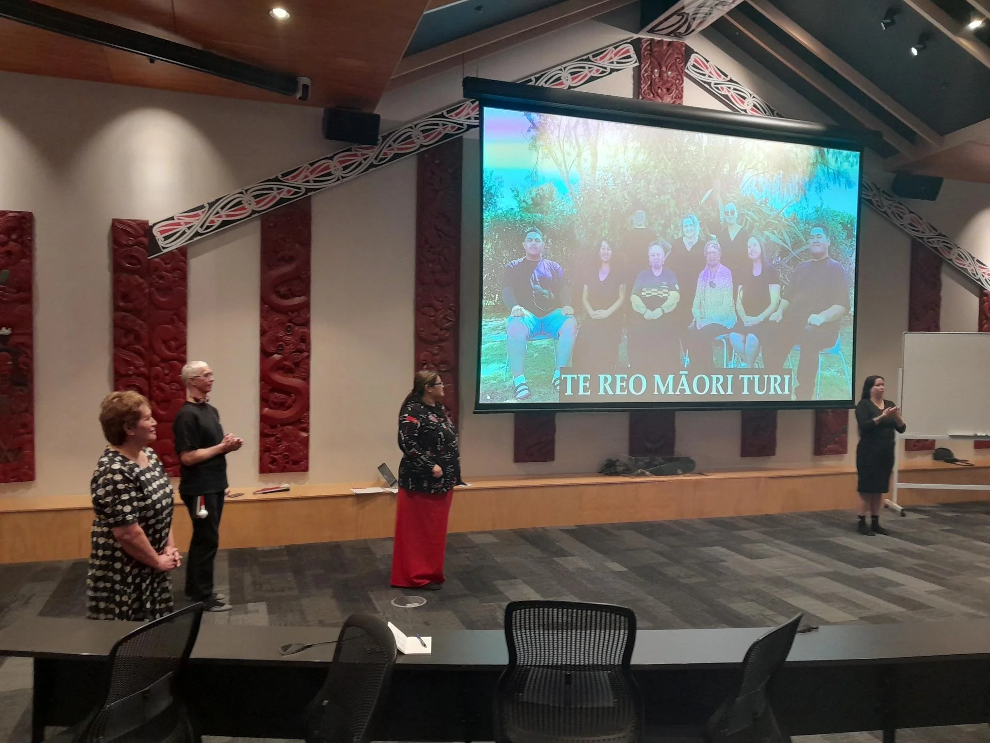 People presenting with projection screen in marae
