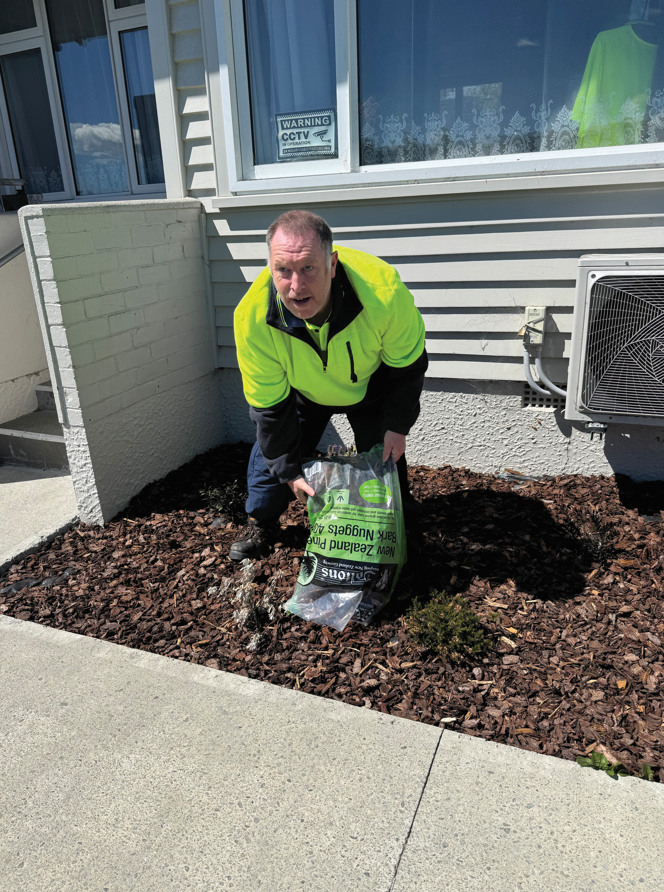 Michael emptying a bag of gardening soil onto his front lawn.