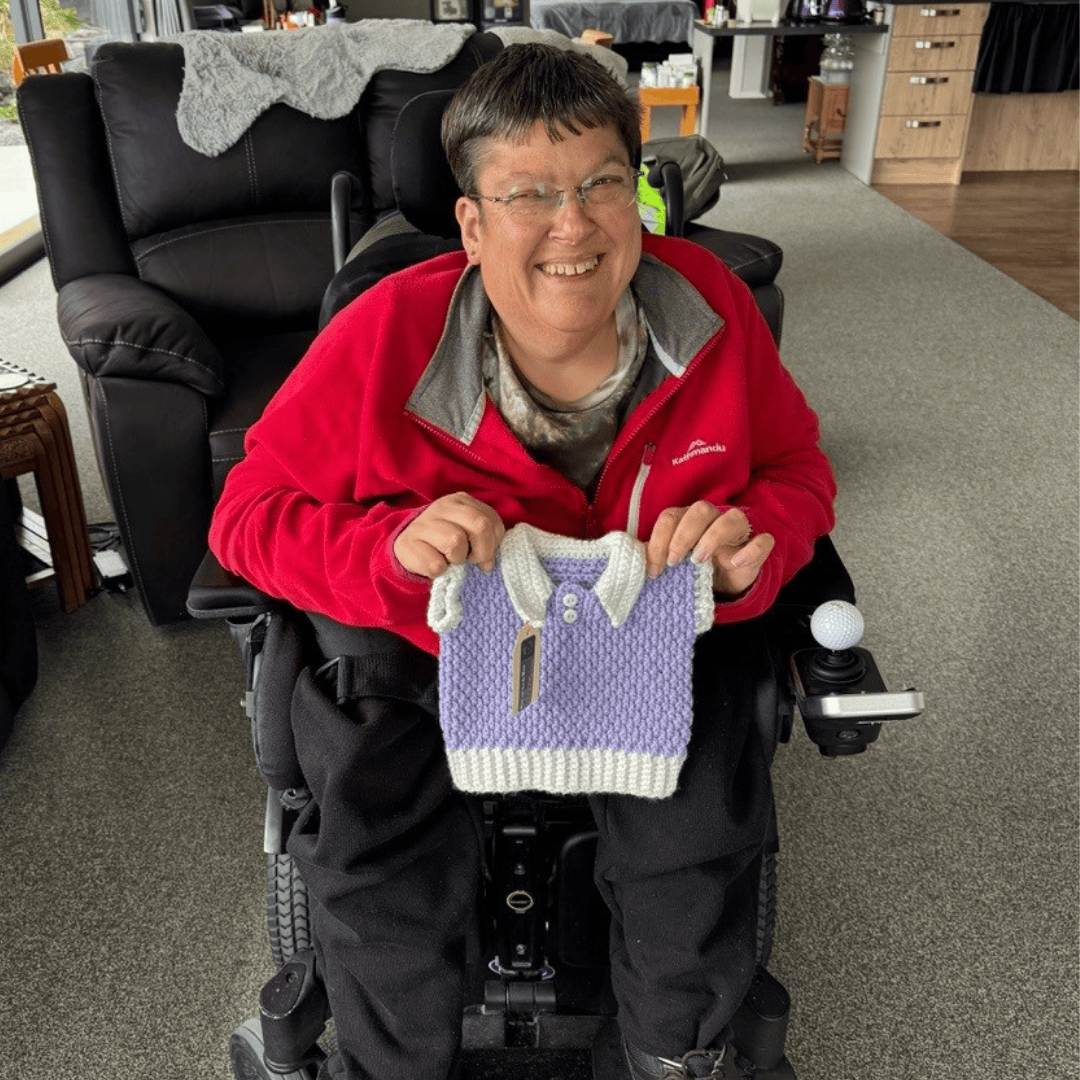 Marie Michie holding one of her crochet creations, a blue toddler's shirt.
