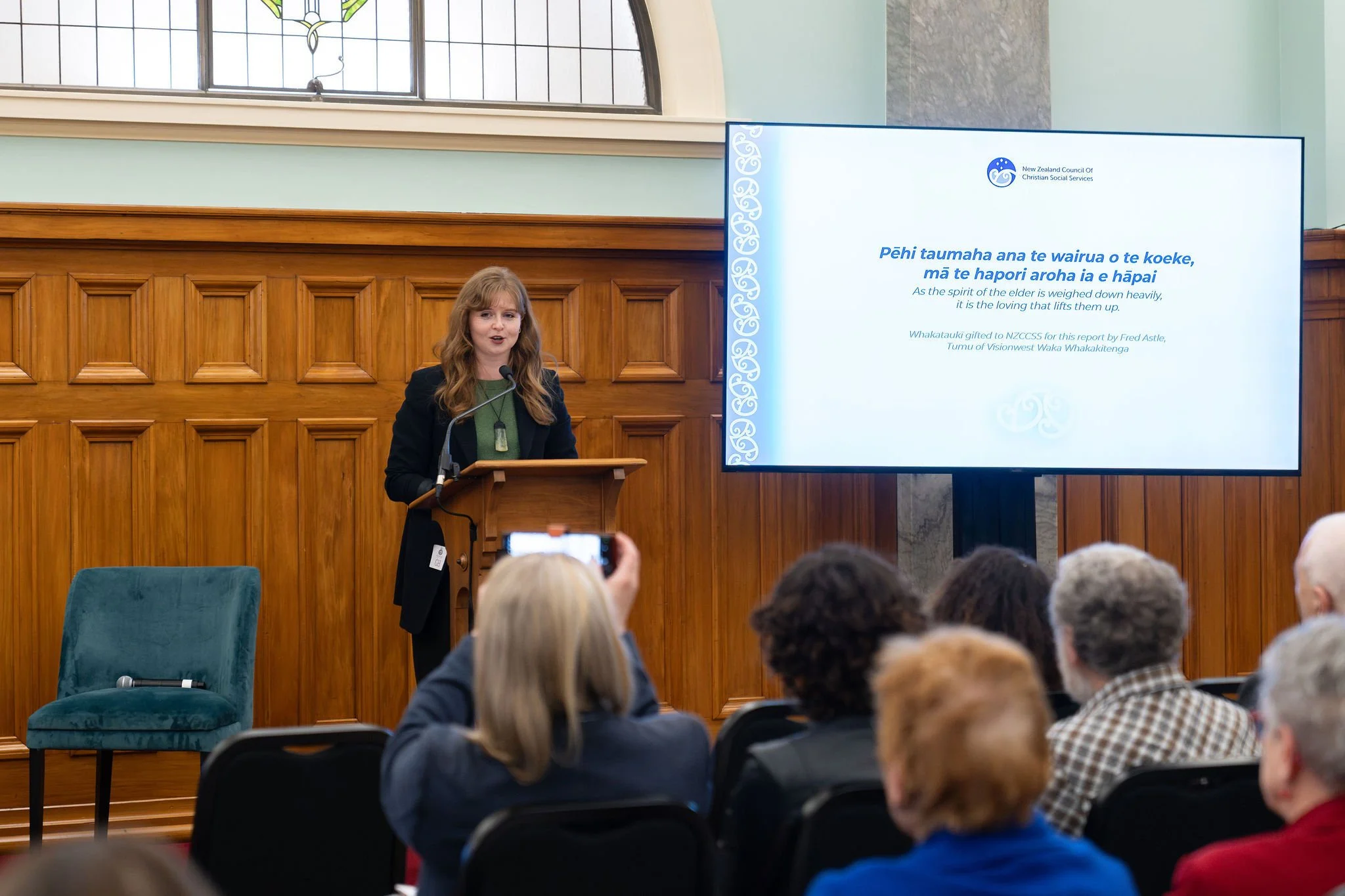 Woman speaking at lectern to audience.