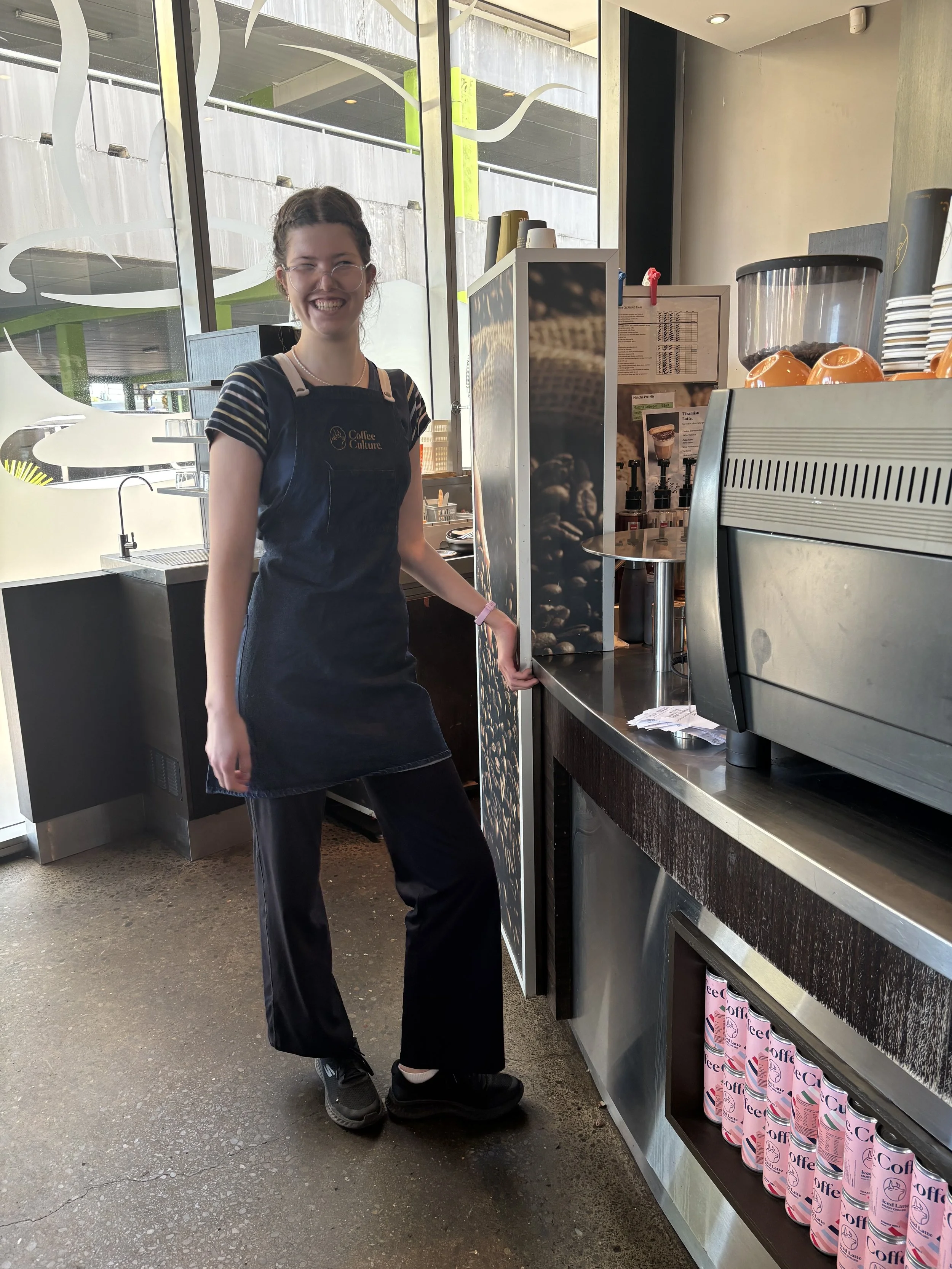 Ruby at work behind the counter, wearing an apron, smiling.