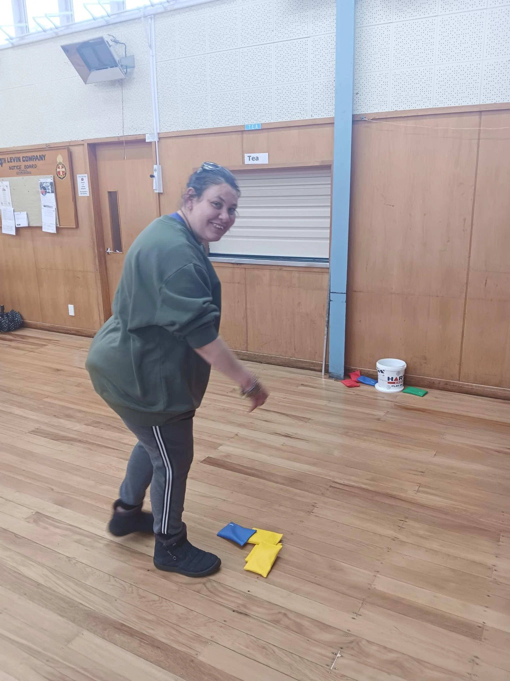Woman smiling as she picks up bean bags