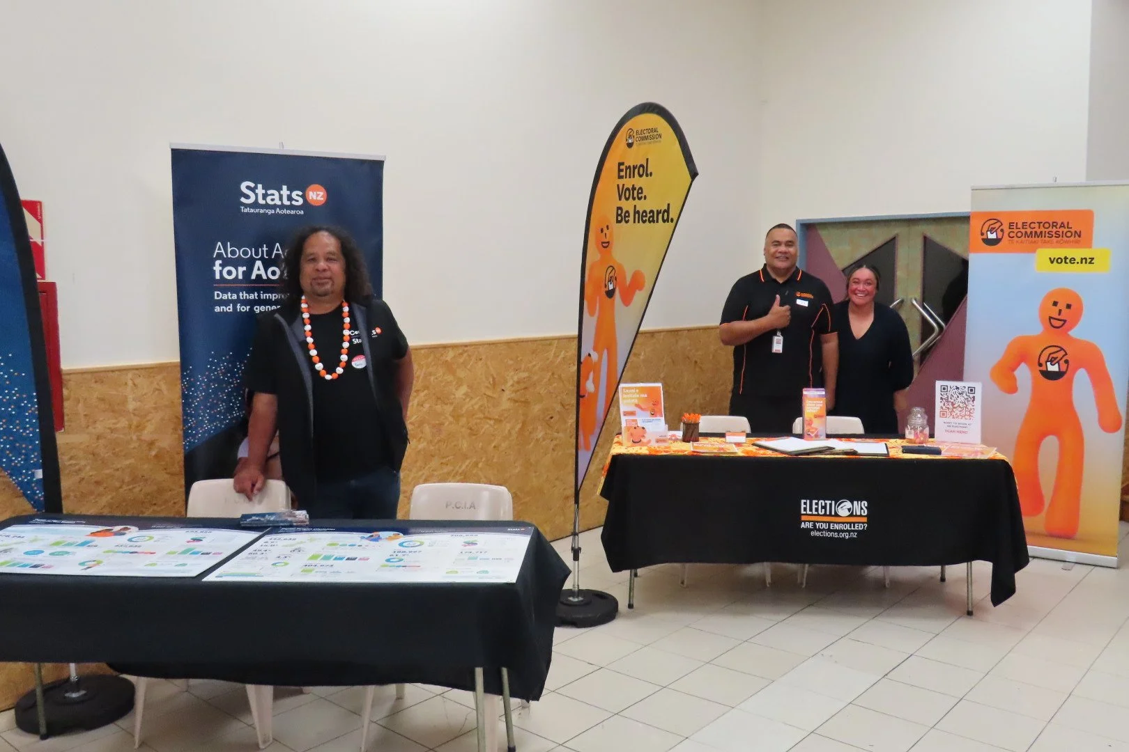 Stats NZ and Electoral Commission staff members stand behind their stalls.