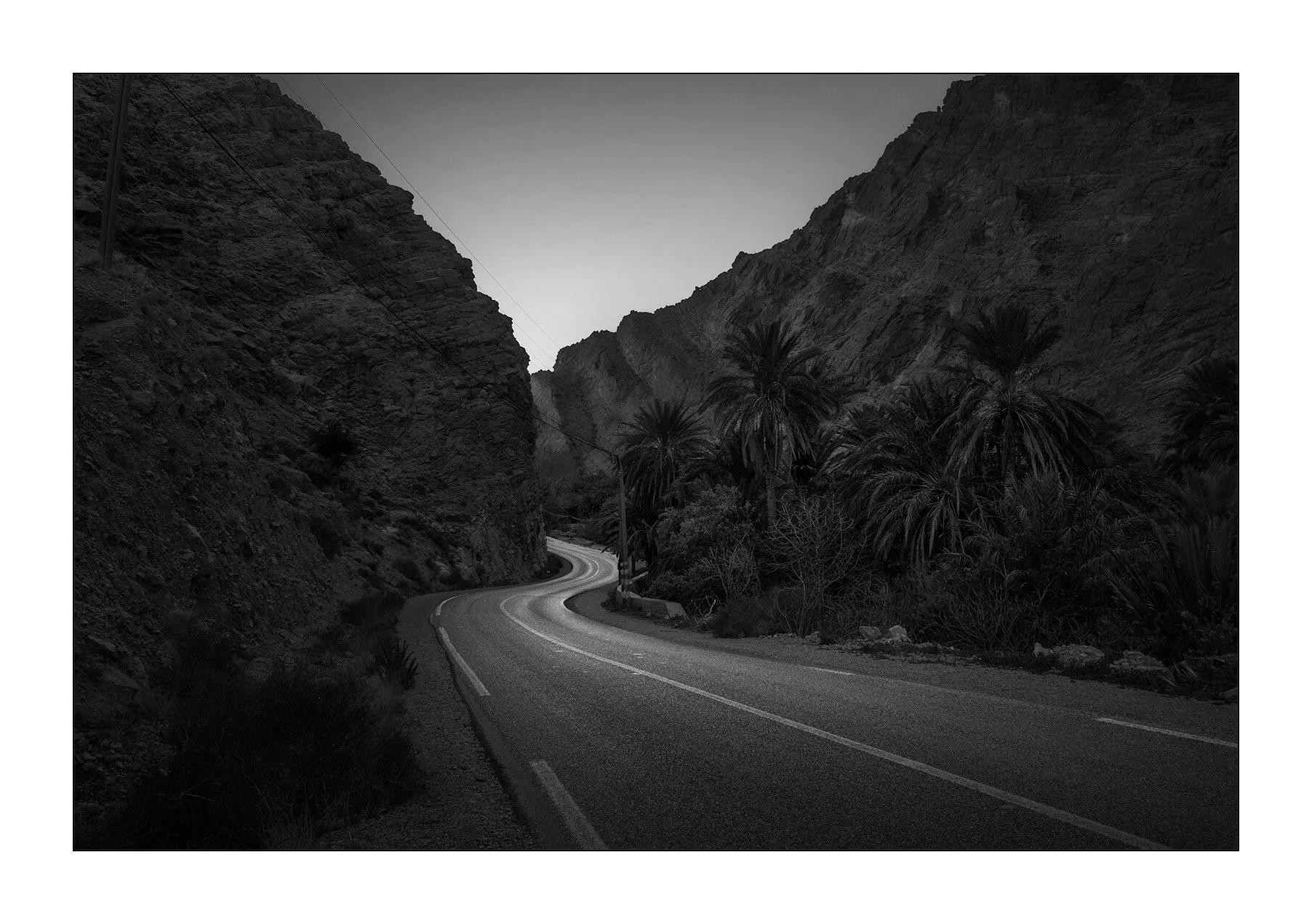 Gorges du Todra, Maroc — une route sinueuse traverse les montagnes entre roche et palmiers.