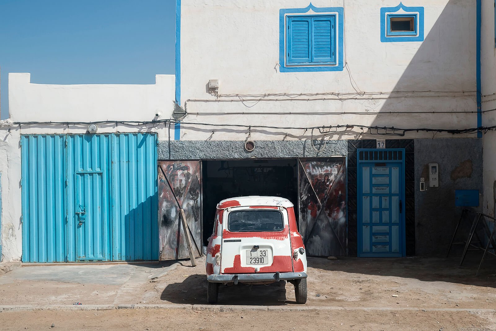 Sidi Ifni, Maroc — une Renault 4 aux couleurs bariolées est stationnée devant un garage.