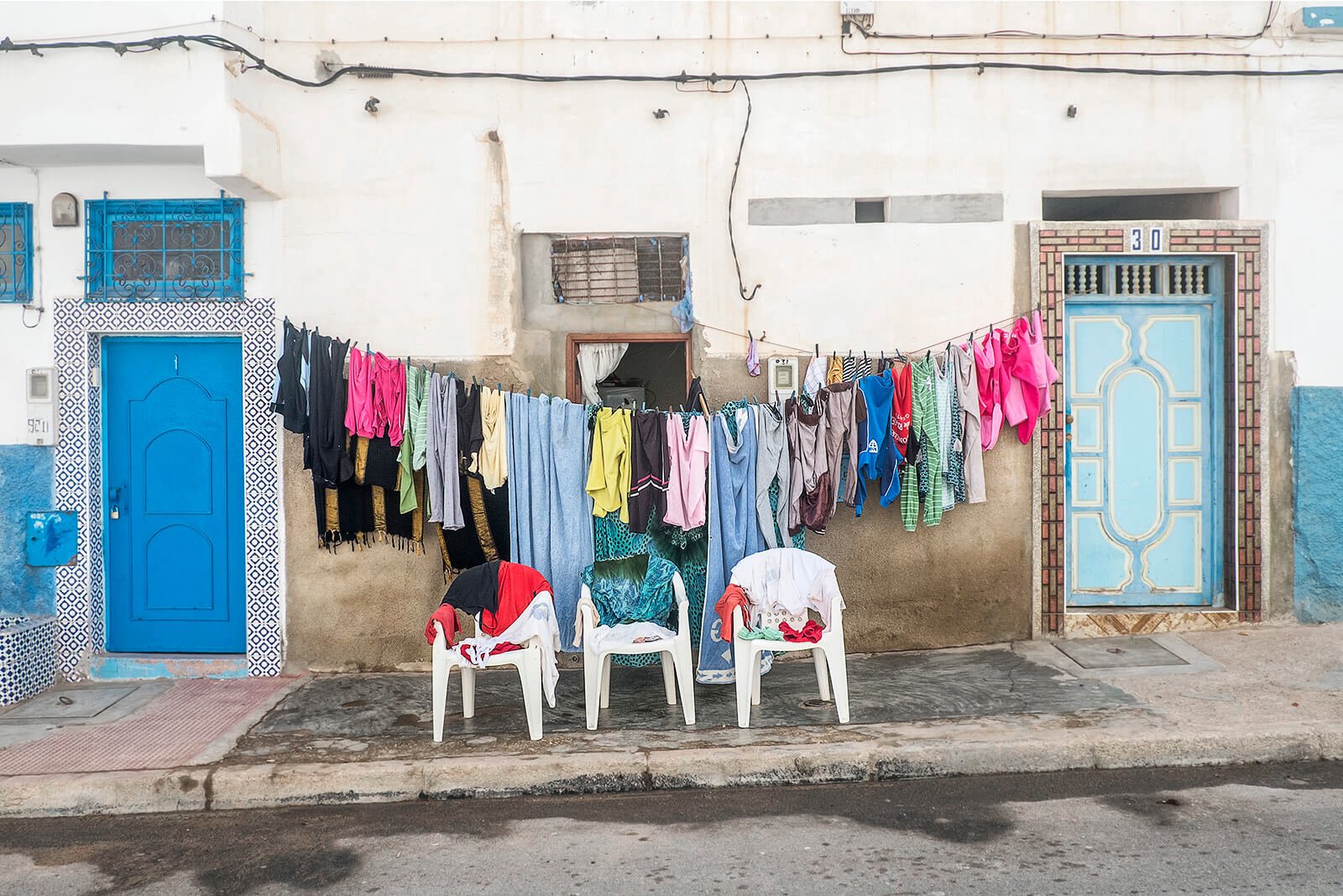 Sidi Ifni, Maroc — du linge coloré sèche sur un fil tendu devant une façade.