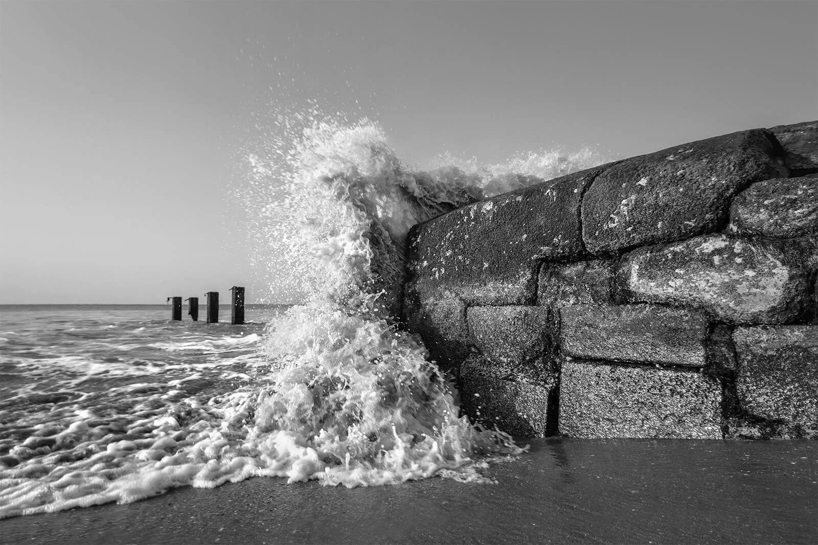 Instant décisif : une vague éclate contre la digue de la Tranche sur mer. Écume blanche éclatante et noirs denses, photographie de mer dynamique.