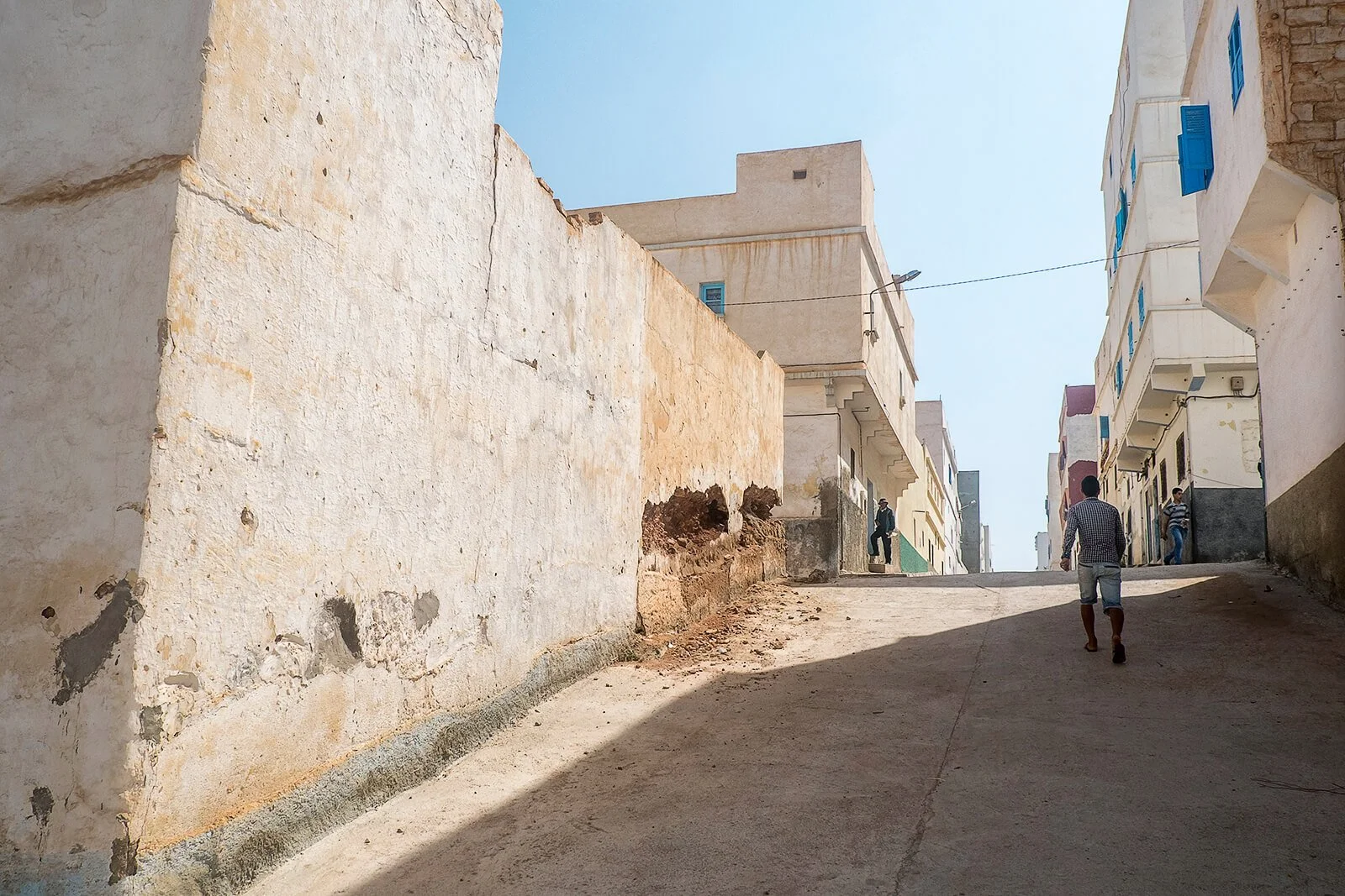 Sidi Ifni, Maroc — une rue en pente monte entre les façades en terre de la ville.