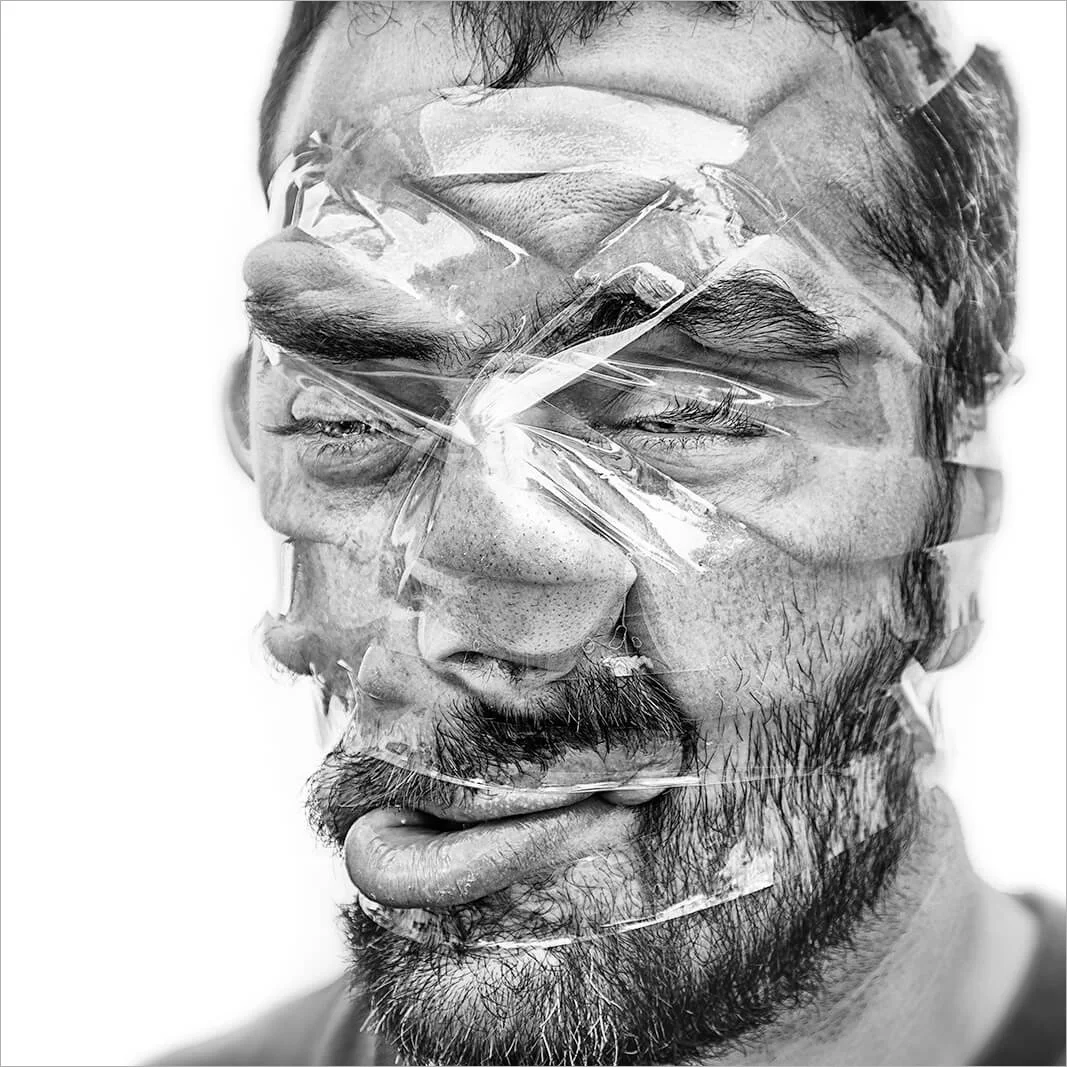 Gros-plan sur un visage tordu par la pression du scotch adhésif. Une photographie humoristique qui explore les limites de l'élasticité de la peau en noir et blanc.
