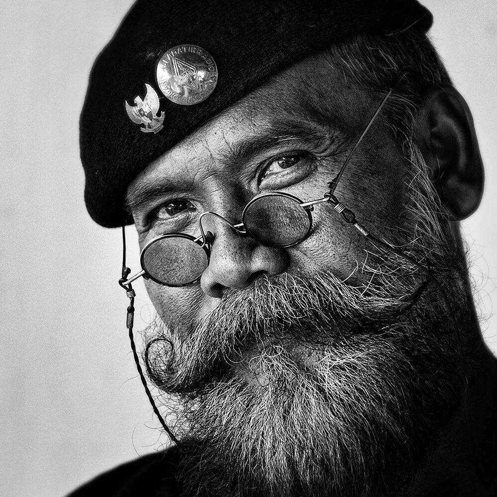 Bali, Indonésie — gros plan sur un homme à la barbe grise qui porte des lunettes rondes et un béret.