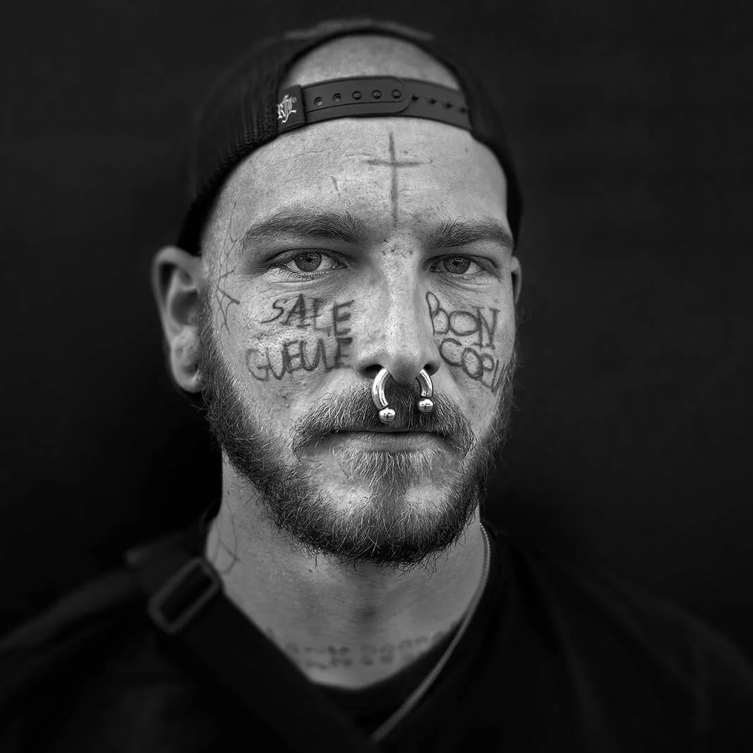 La Roche-sur-Yon, France — portrait serré d’un jeune homme portant des tatouages sur le visage et un large anneau dans le nez.