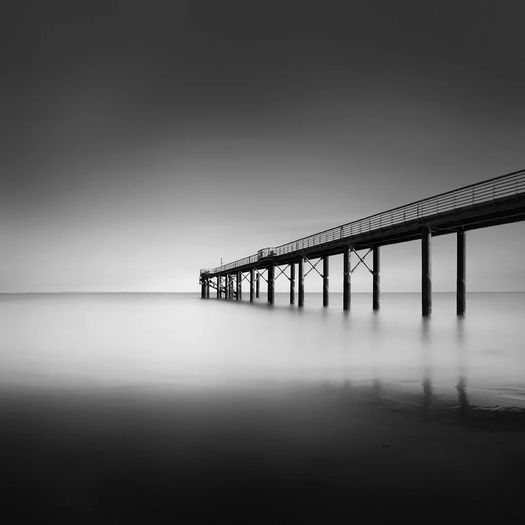 Photographie d'art noir et blanc de l'embarcadère de La Tranche-sur-Mer. Perspective graphique et lignes de fuite vers l'horizon. Signé Hugues Hardy.