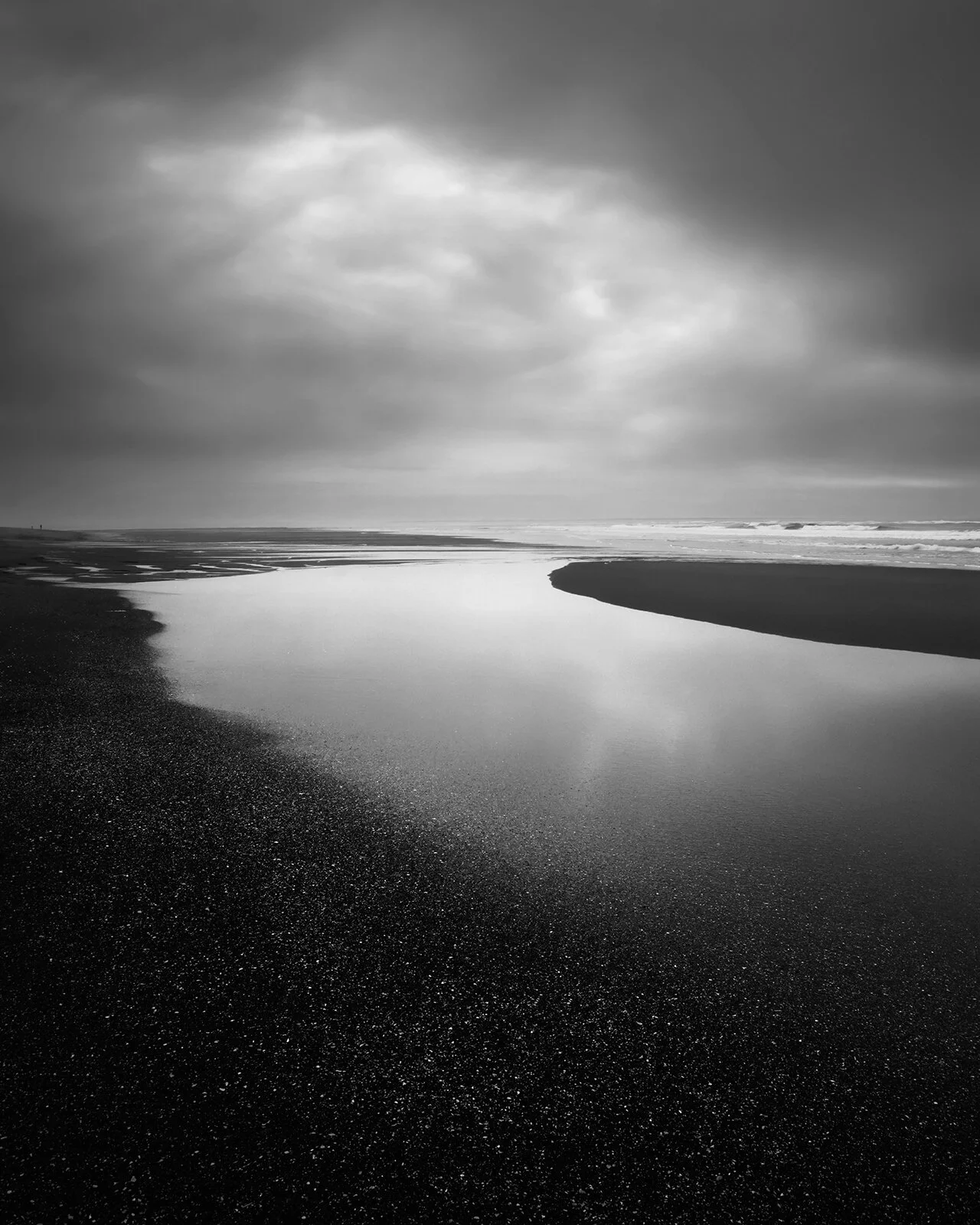 Lignes de fuite sur une plage de la Tranche sur mer : l'eau se retirant sur le sable mouillé vers l'horizon. Texture de l'eau et reflets en noir et blanc.