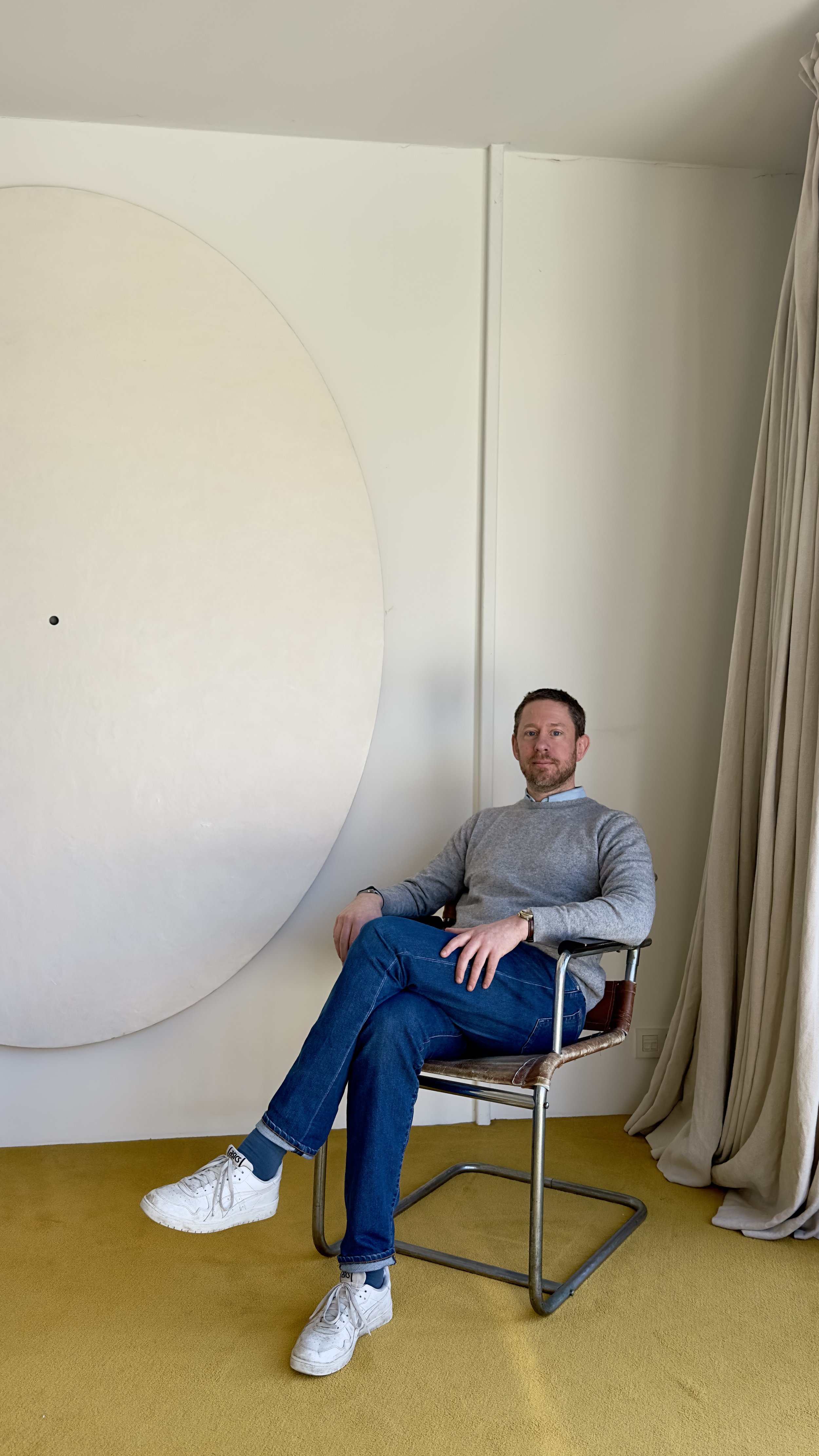 Arthur at home sitting a chair in front of a Michael Rey piece