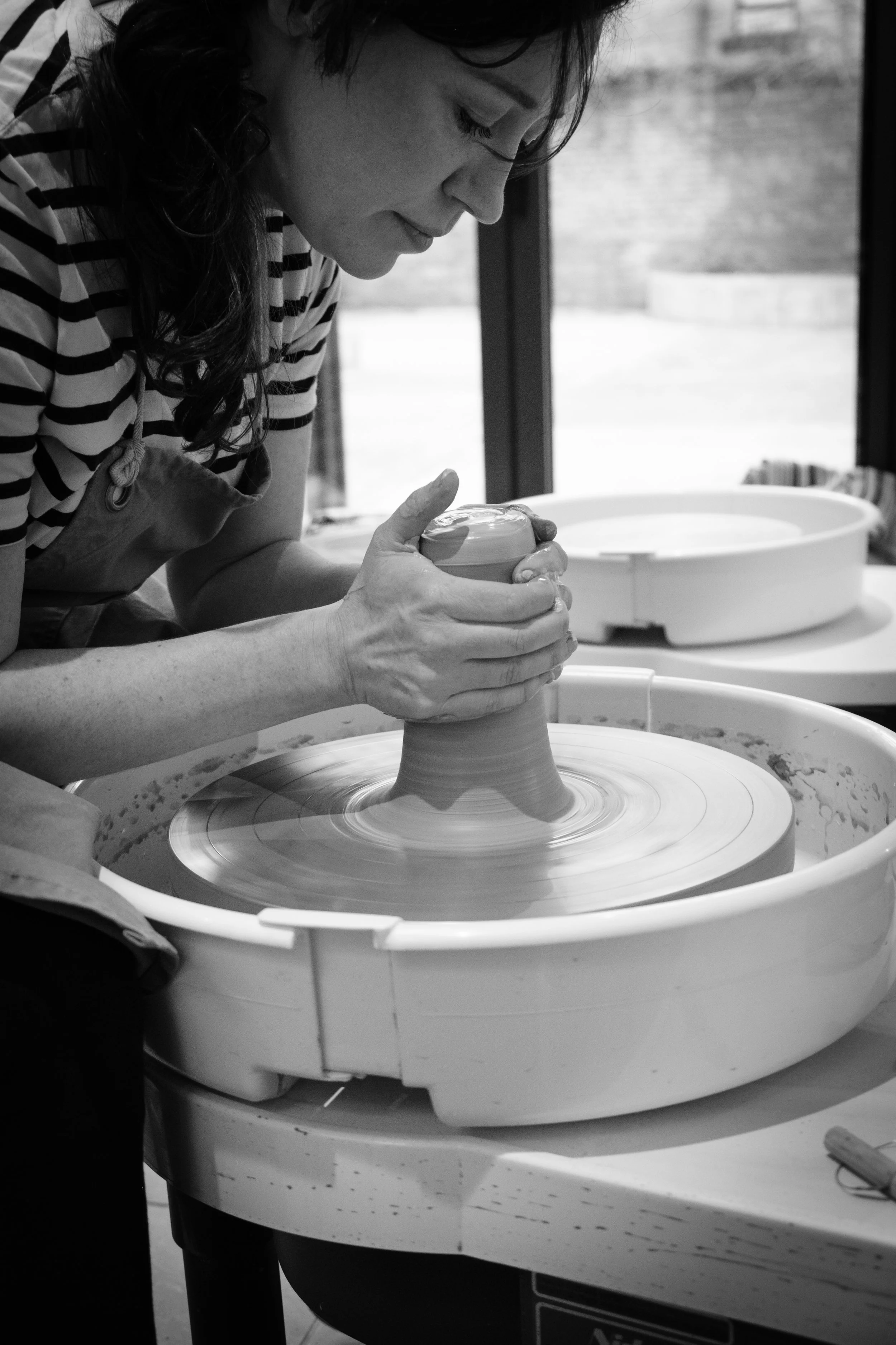 Kim Plimley on her pottery wheel prepping clay for pulling
