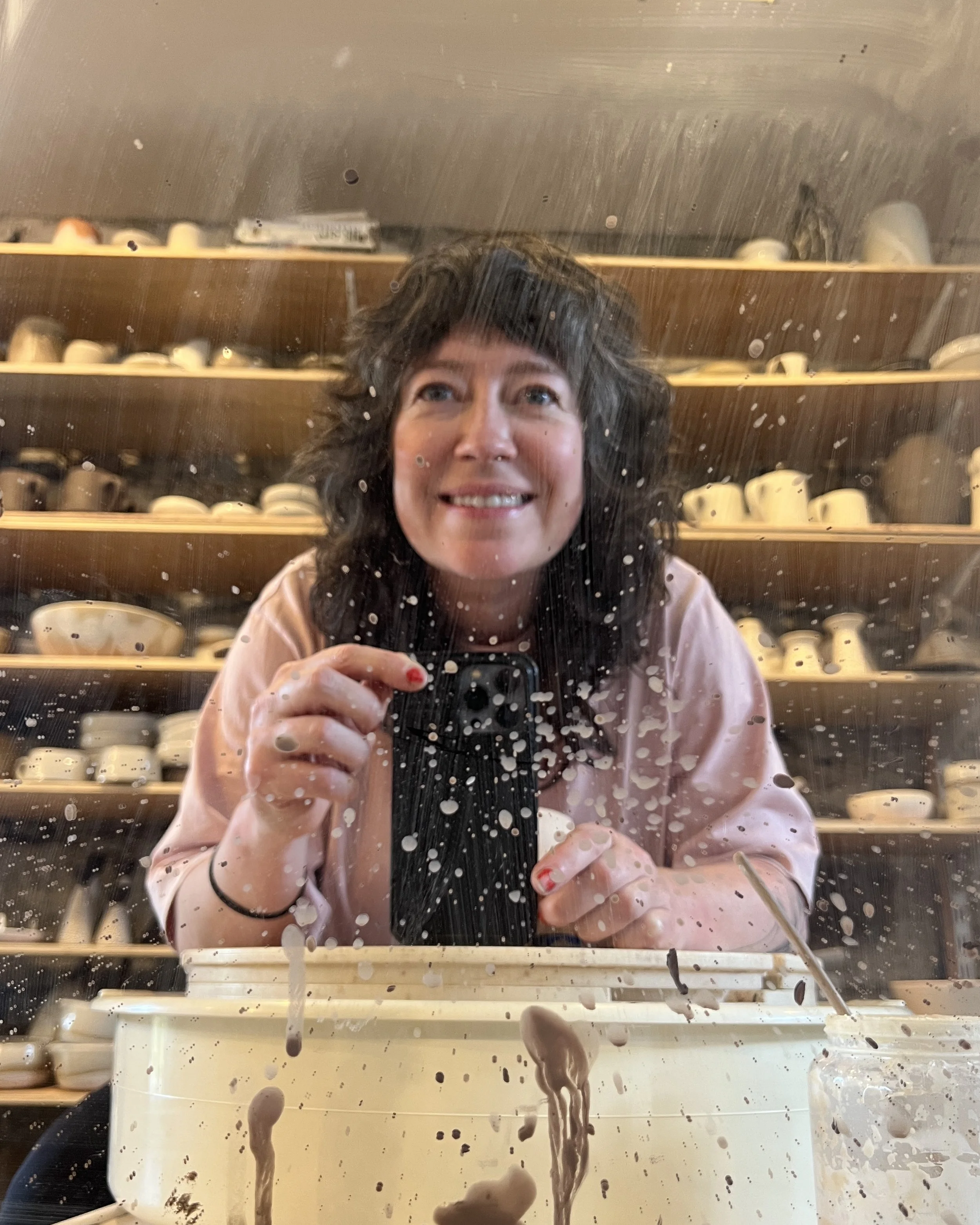Kim Plimley in her ceramics studio, glazing pottery surrounded by handmade stoneware