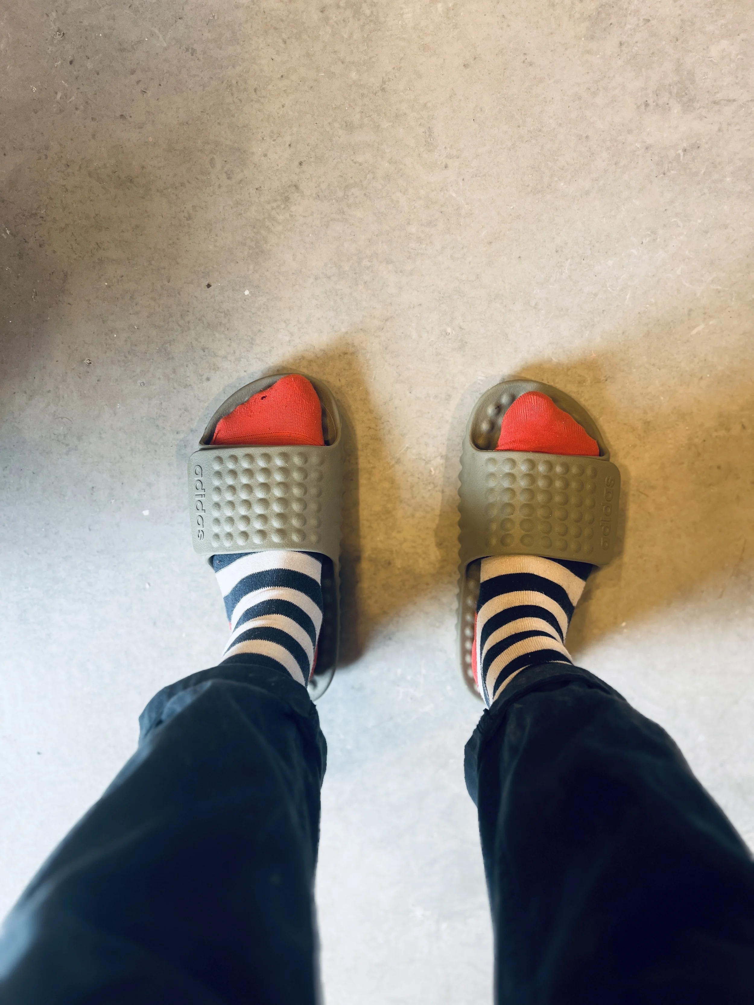 Striped socks and slip on sandals on the concrete floor of Kim Plimley's home pottery studio