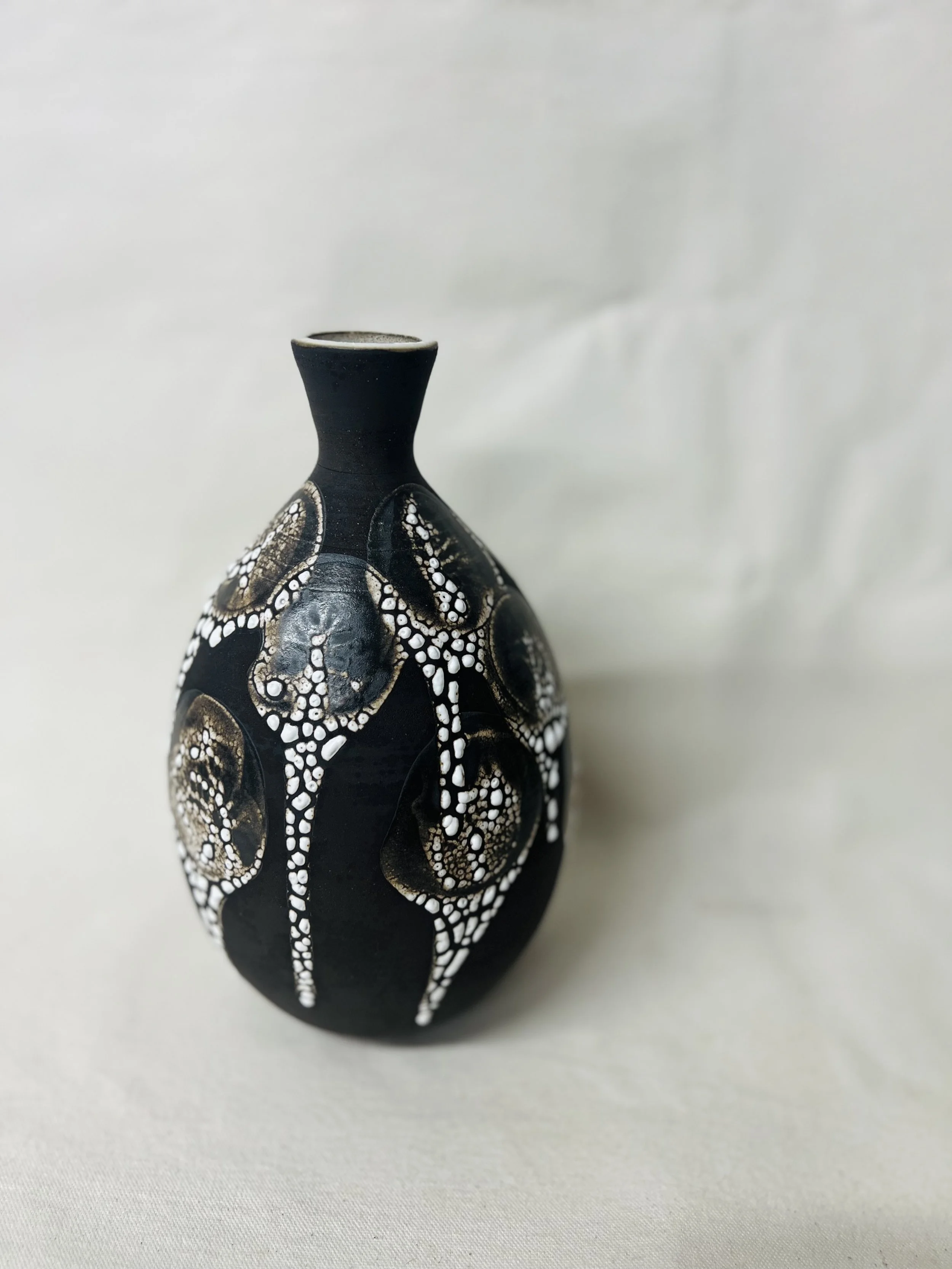 A black decorative vase with white and gold circular patterns.