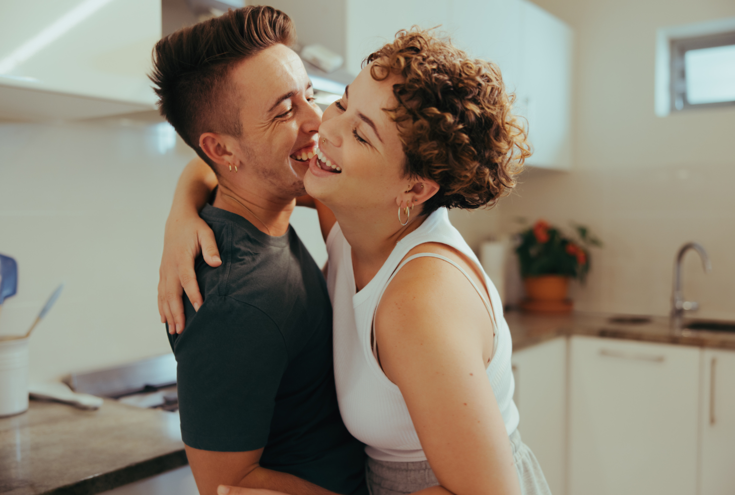 A joyful couple hugging and smiling in a kitchen.
