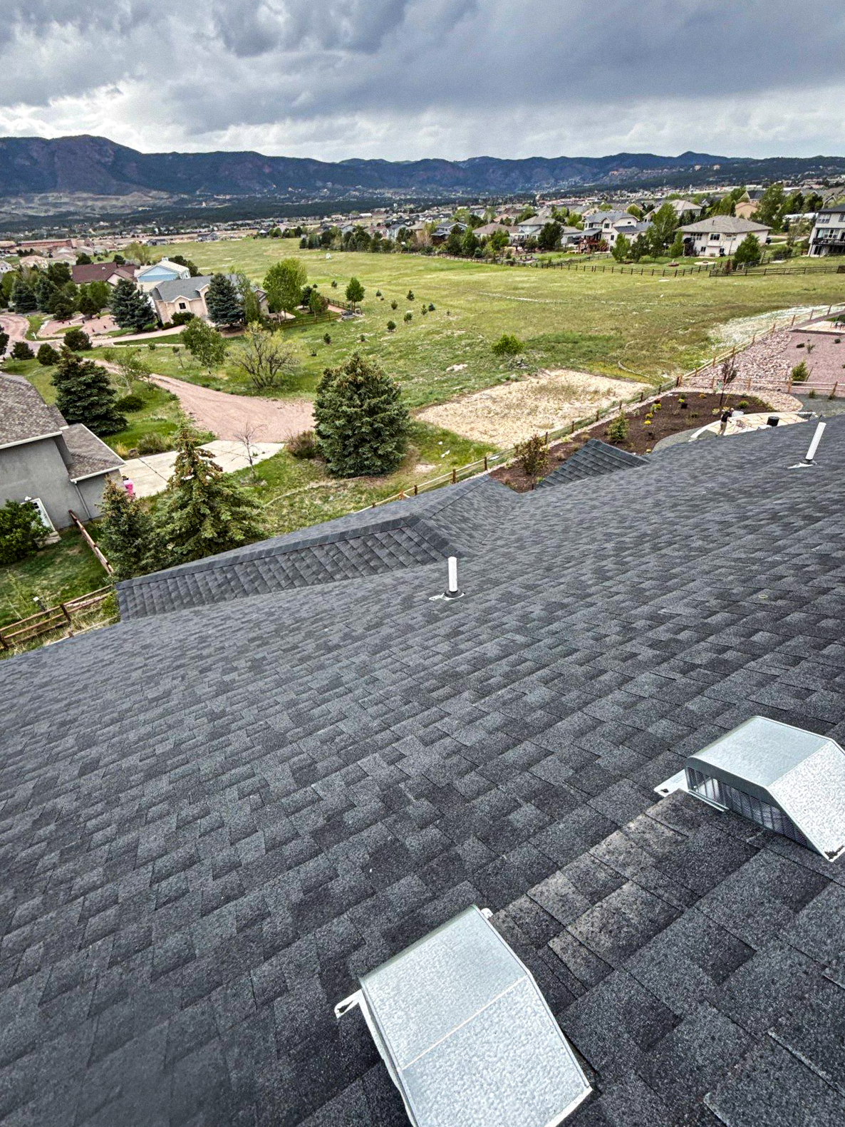 An AVI Roofing inspection photo featuring a residential roof and the Colorado Rockies in the background.