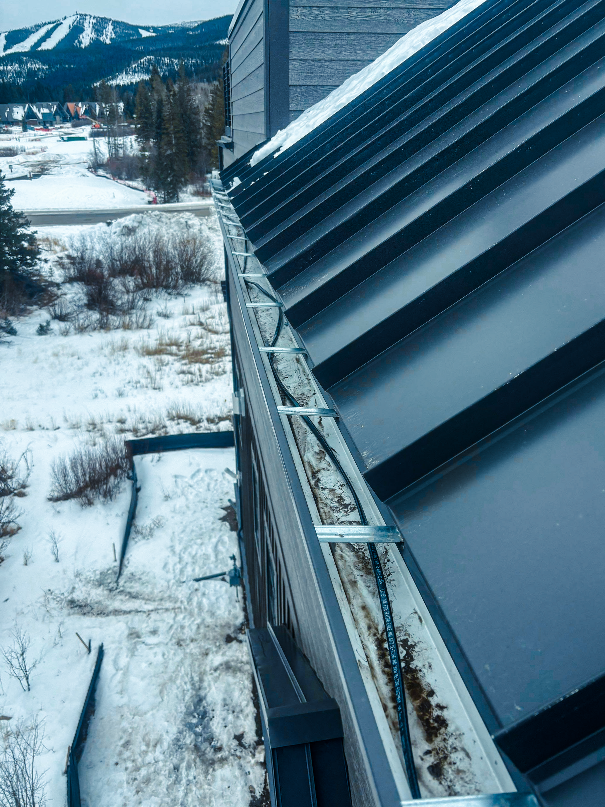 A metal roof system and steel gutter system which has heat tape professionally installed within the gutter to help alleviate snow dams during the winter
