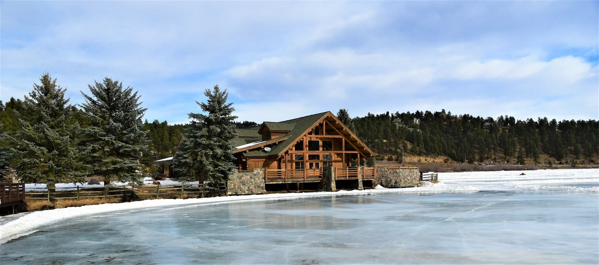 A mountain home in Evergreen sits surrounded by snow and a frozen lake.