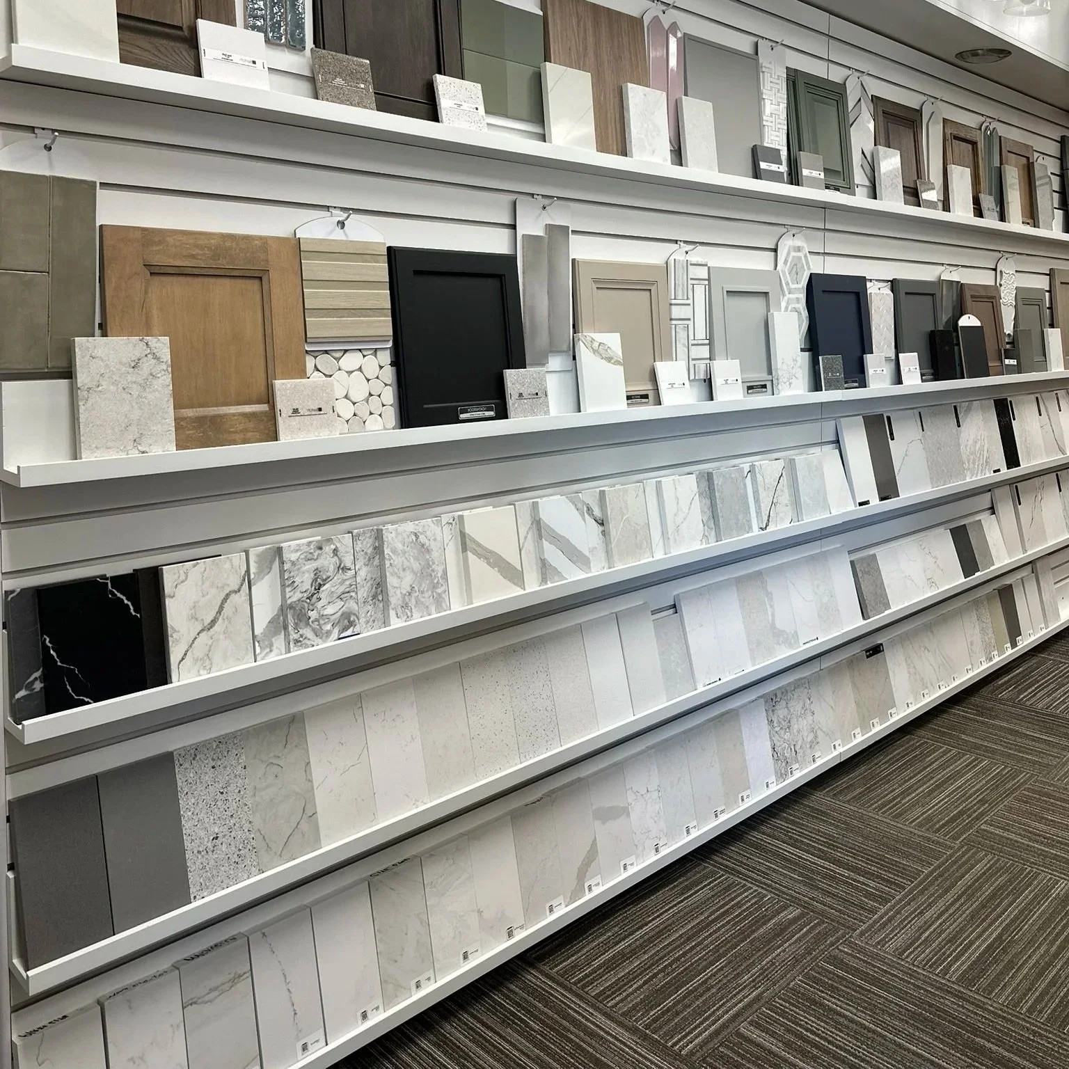 Display of tile and flooring samples at a home improvement store, including wood, stone, and patterned tiles.