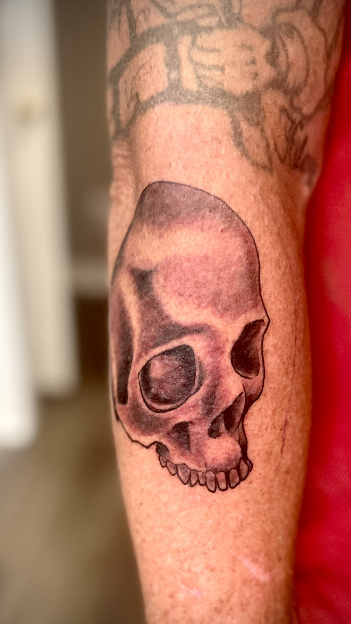 Tattoo of a human skull on a person's arm.