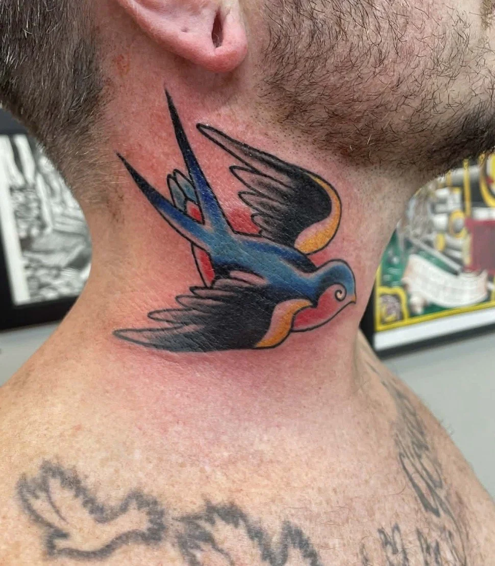 Colorful swallow tattoo on man's neck