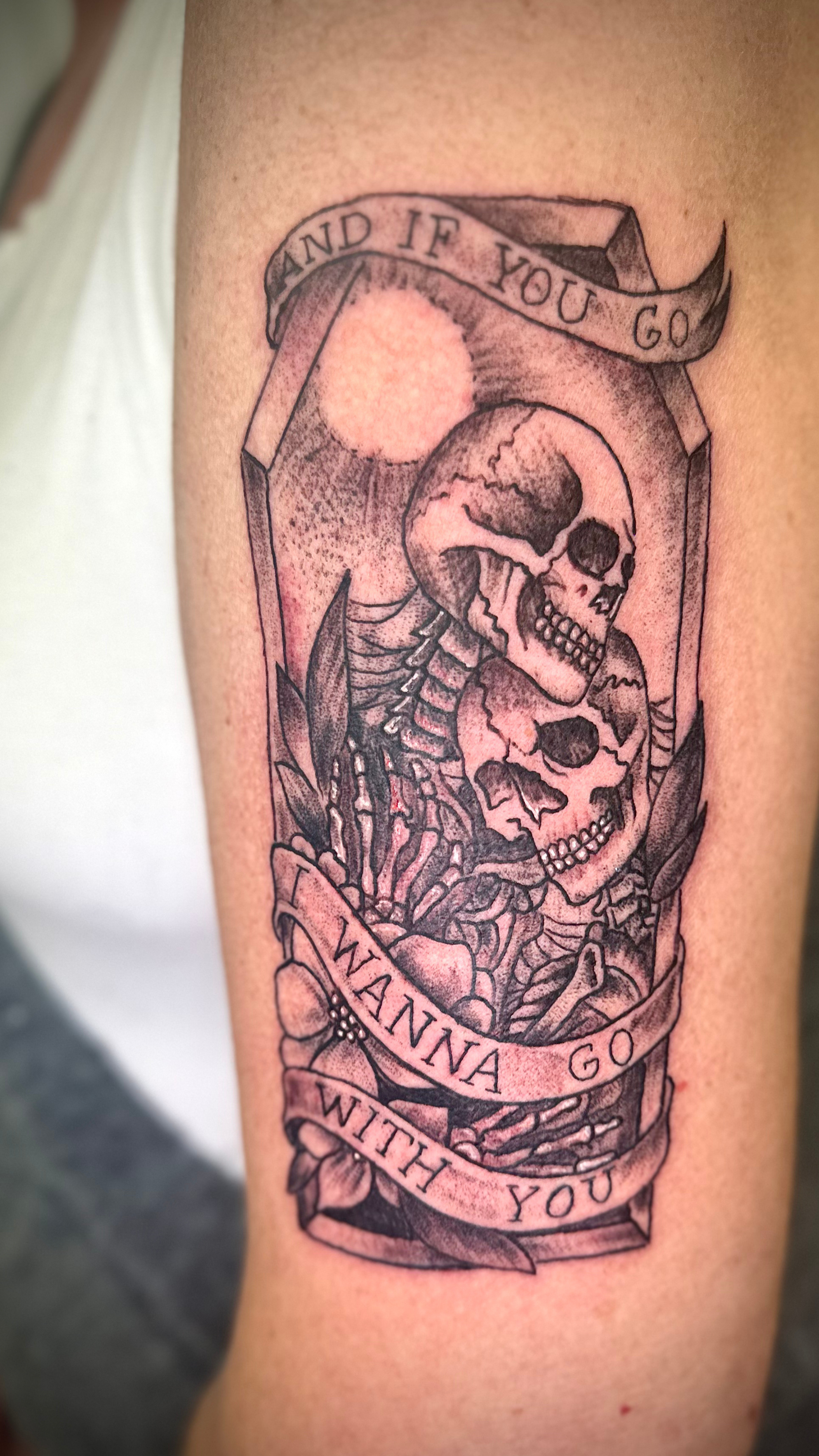 Tattoo of a skeleton holding a skull with a ribbon that reads "And if you go, I want you to go with you."