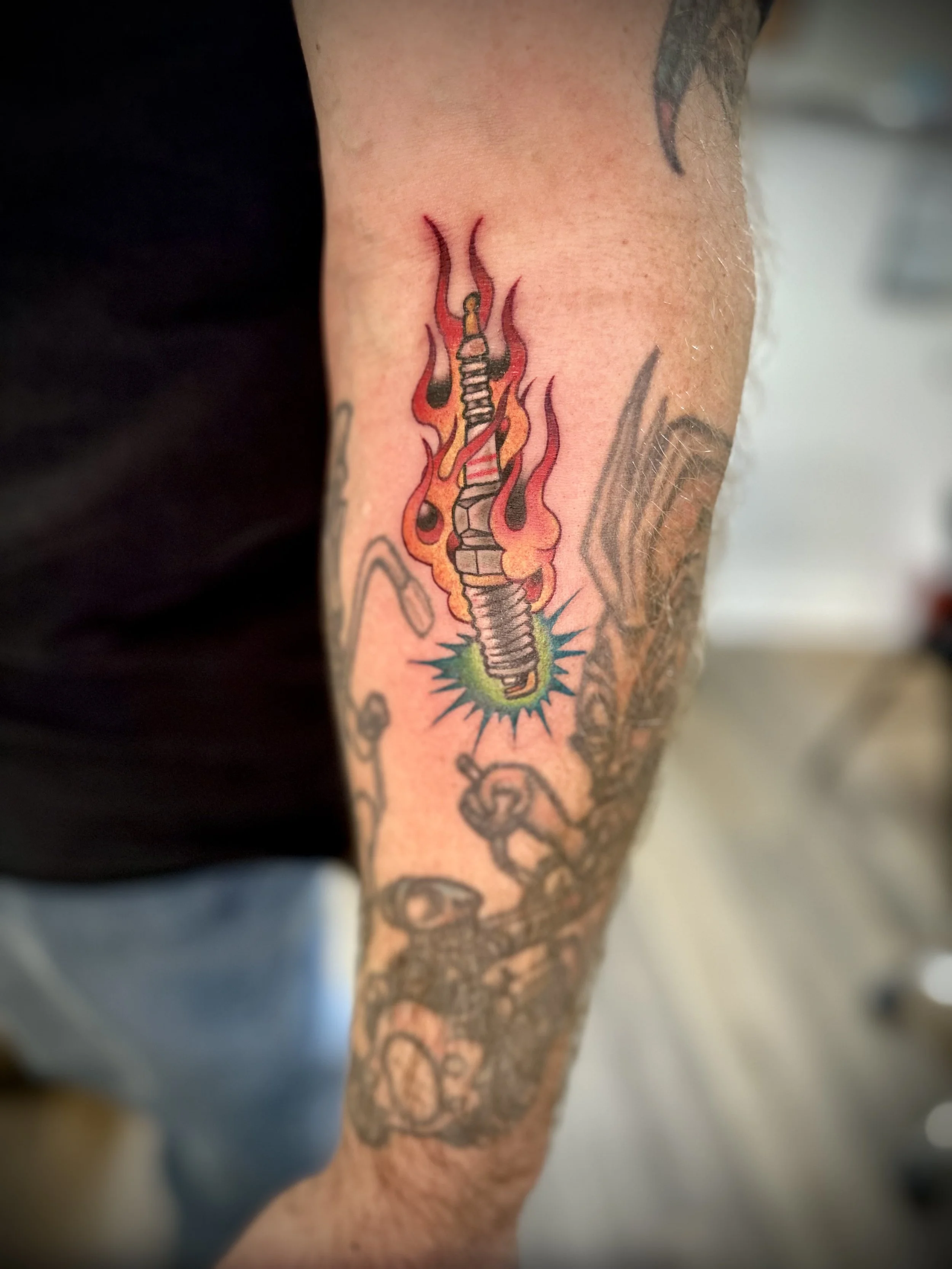 Tattoo of a flaming sword with a bandage wrapped around it on a person's arm.