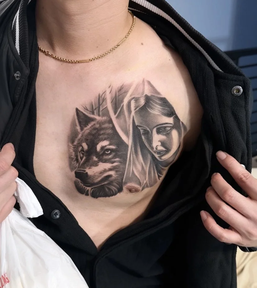 Tattoo of a wolf and a woman's face on a person's chest.